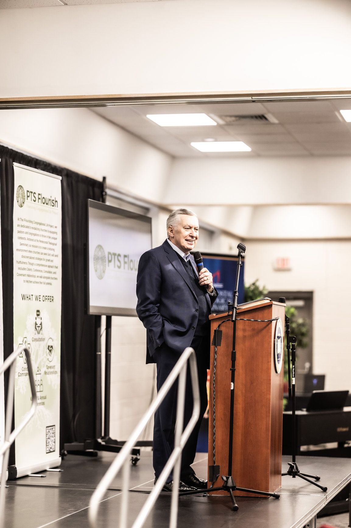 A man in a suit is standing at a podium giving a speech.