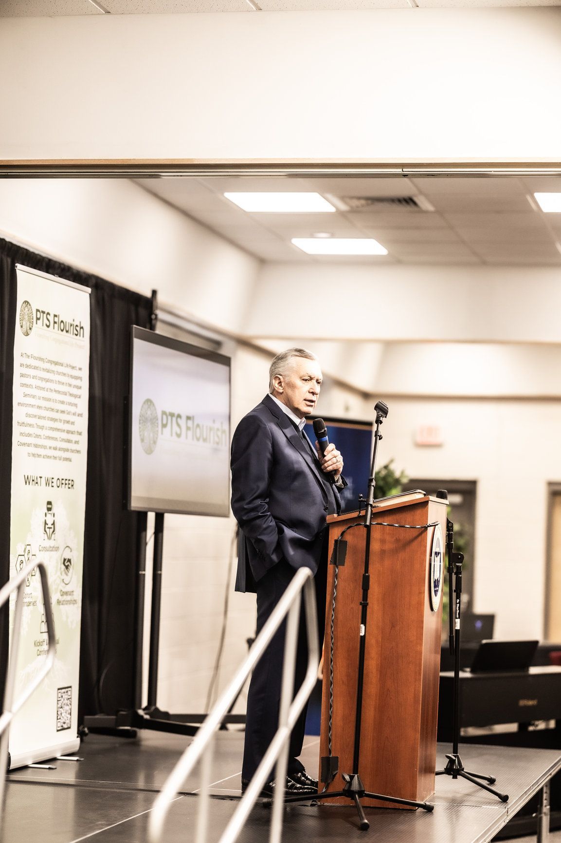 A man in a suit is standing at a podium giving a speech.