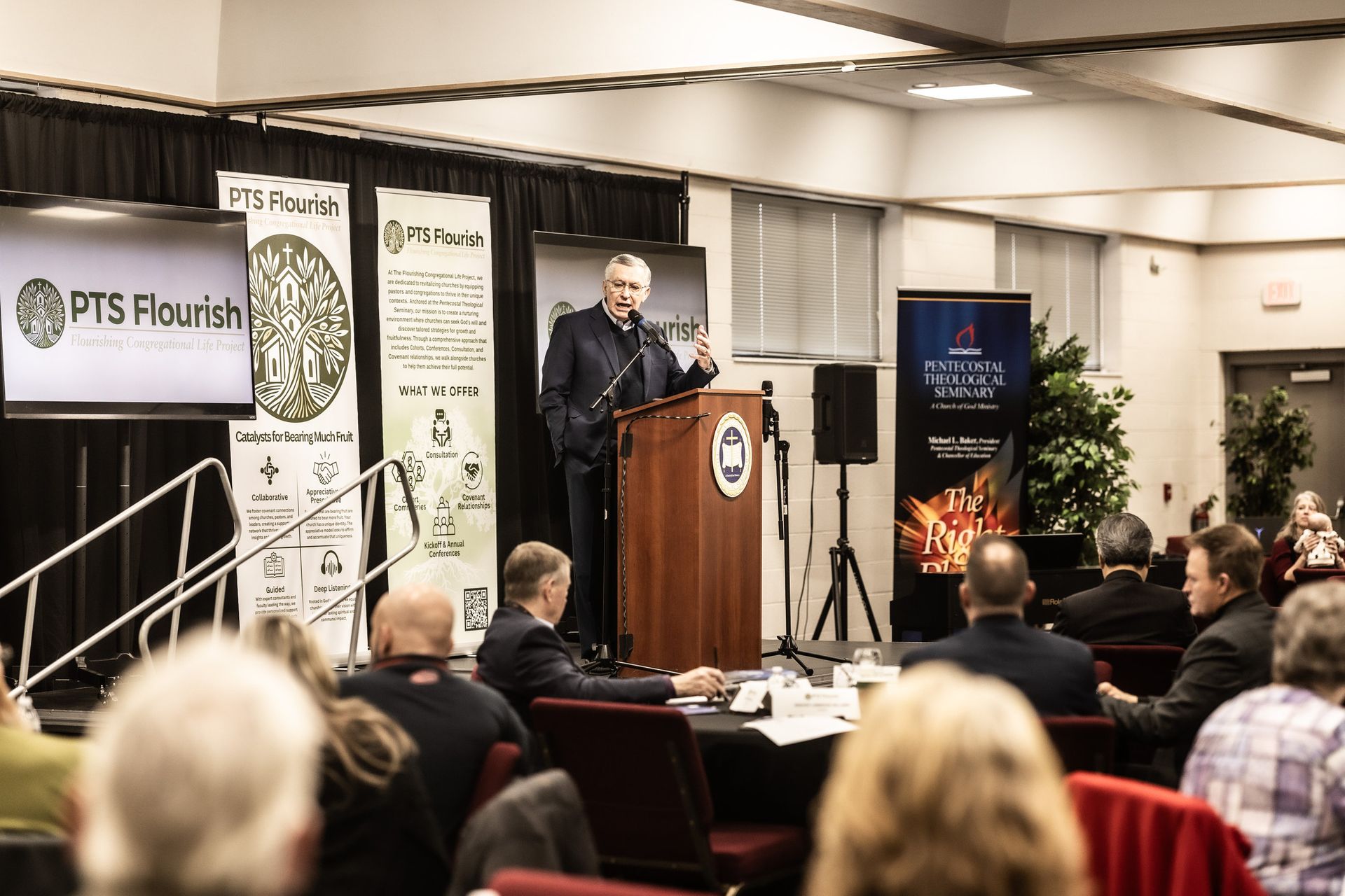 A man stands at a podium giving a speech to a group of people