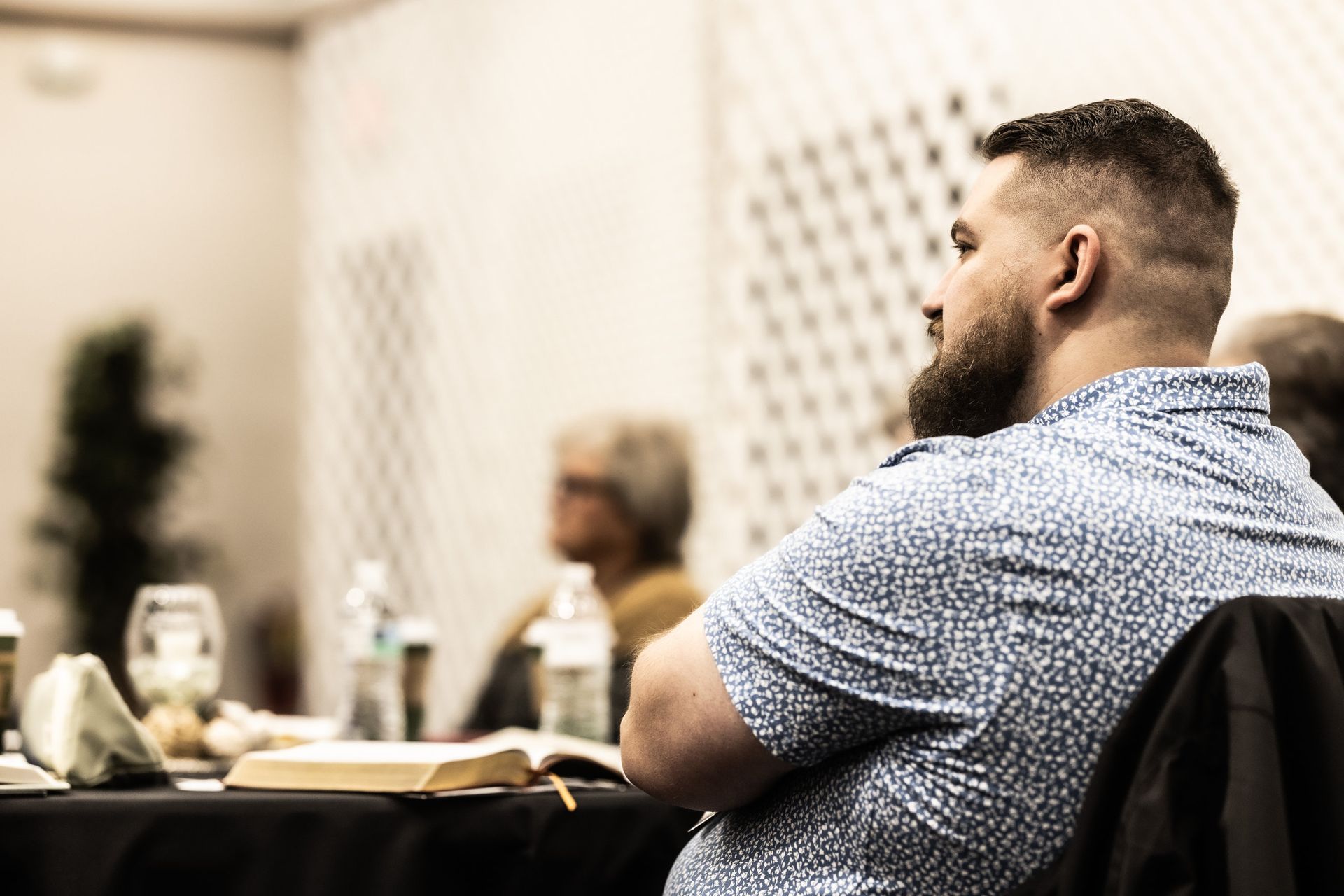 A man with a beard is sitting at a table with a bible.