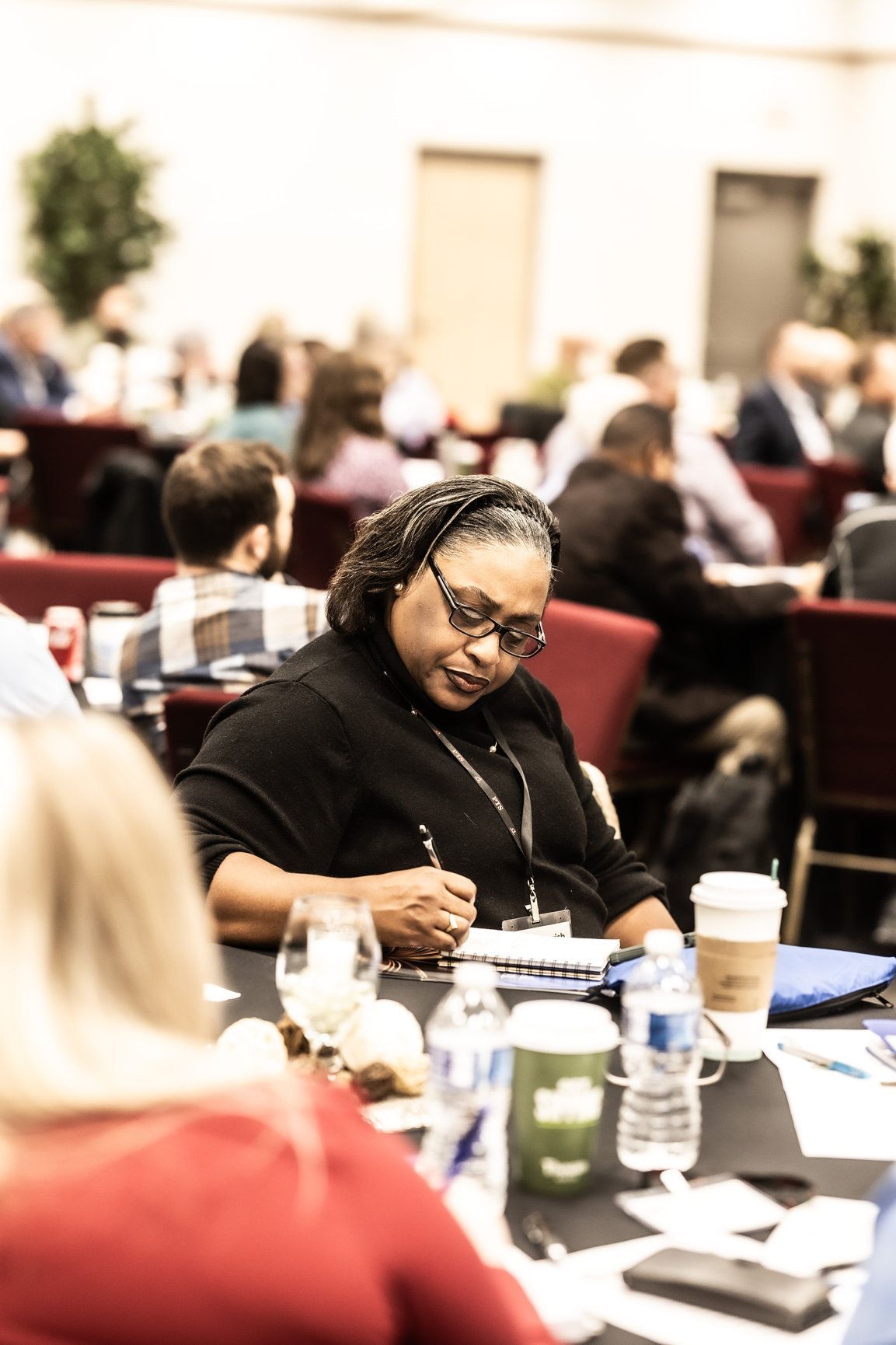 A woman is sitting at a table in a crowded room.