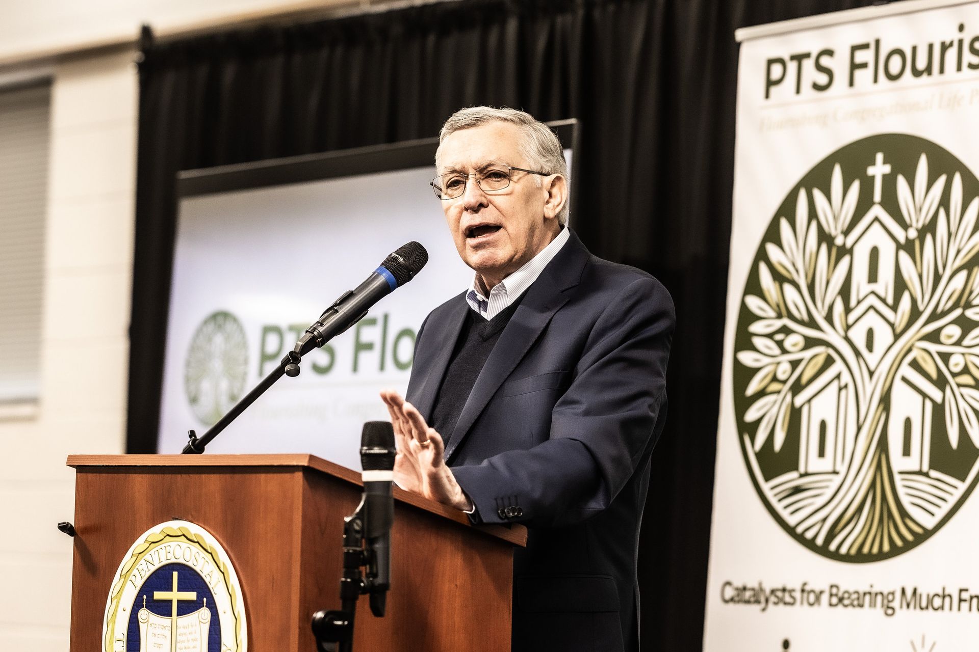 A man is standing at a podium speaking into a microphone.