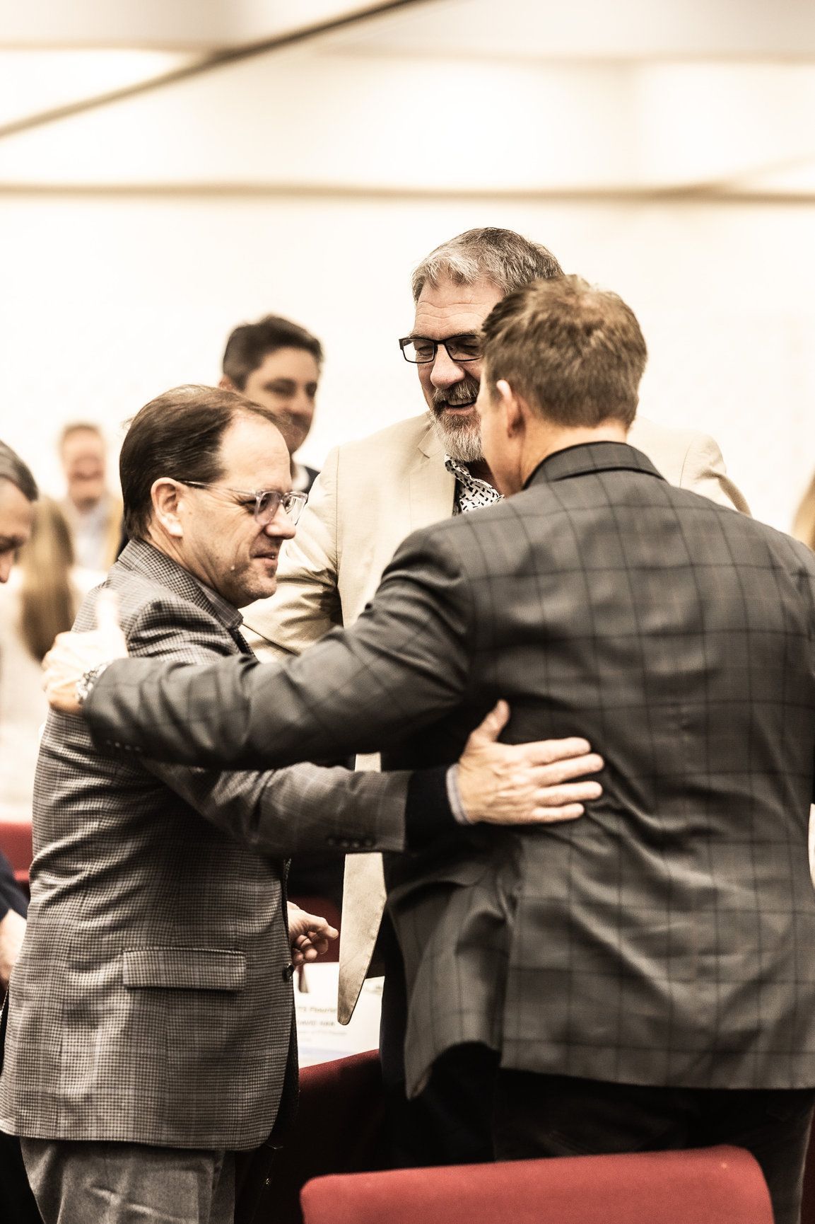 A group of men are hugging each other in a room.