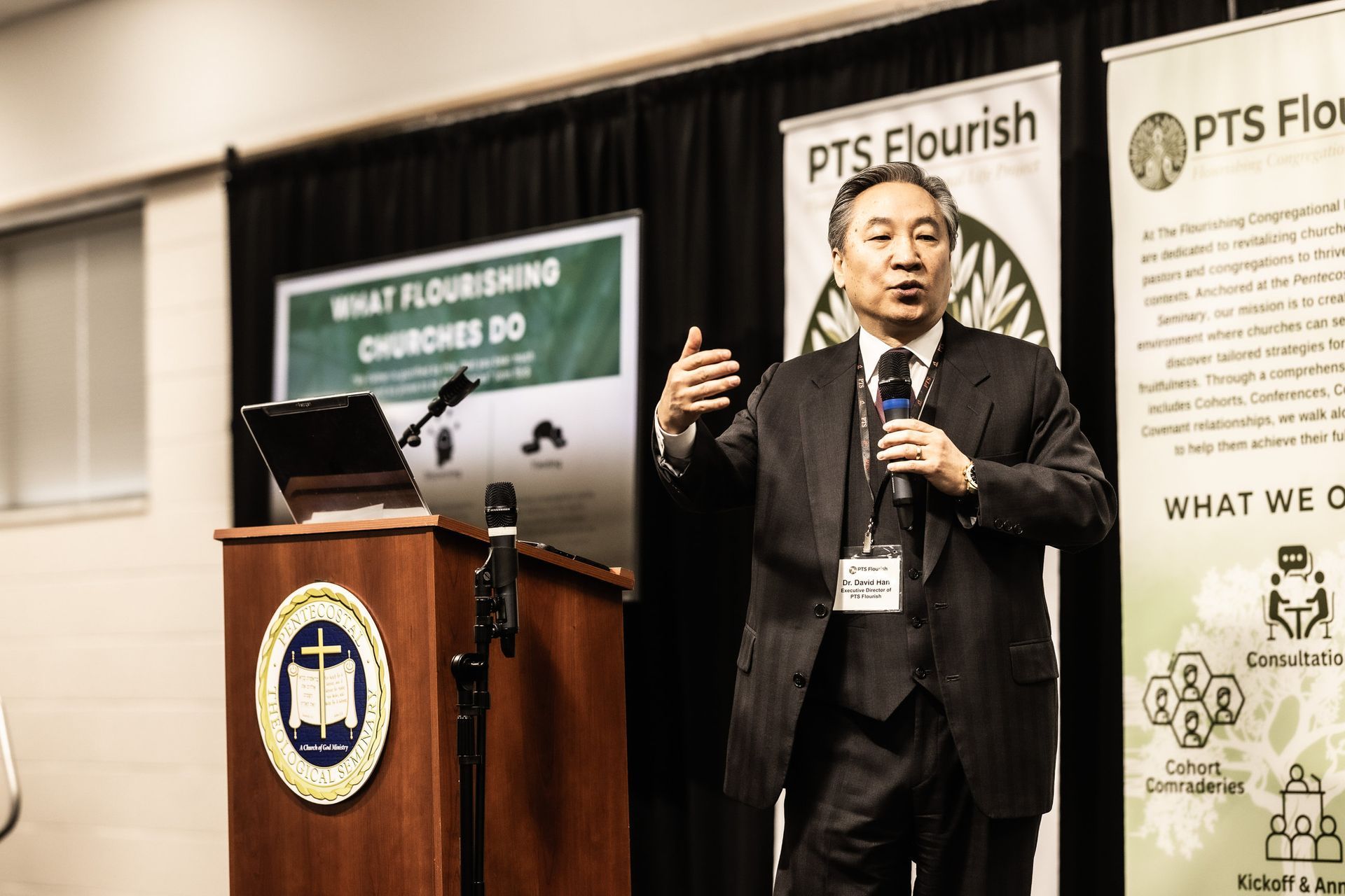 A man in a suit and tie is standing at a podium giving a presentation.