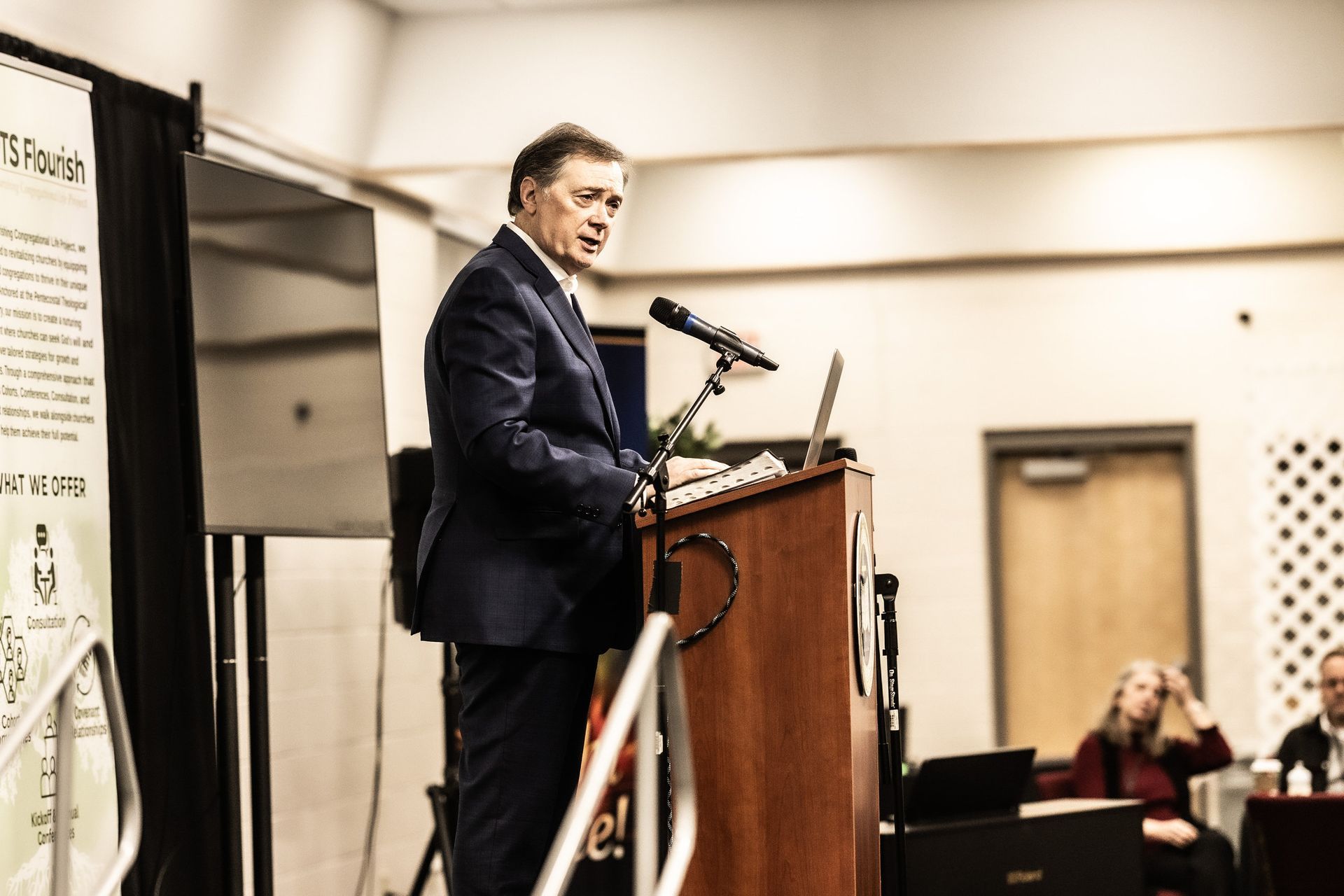 A man in a suit is standing at a podium giving a speech.