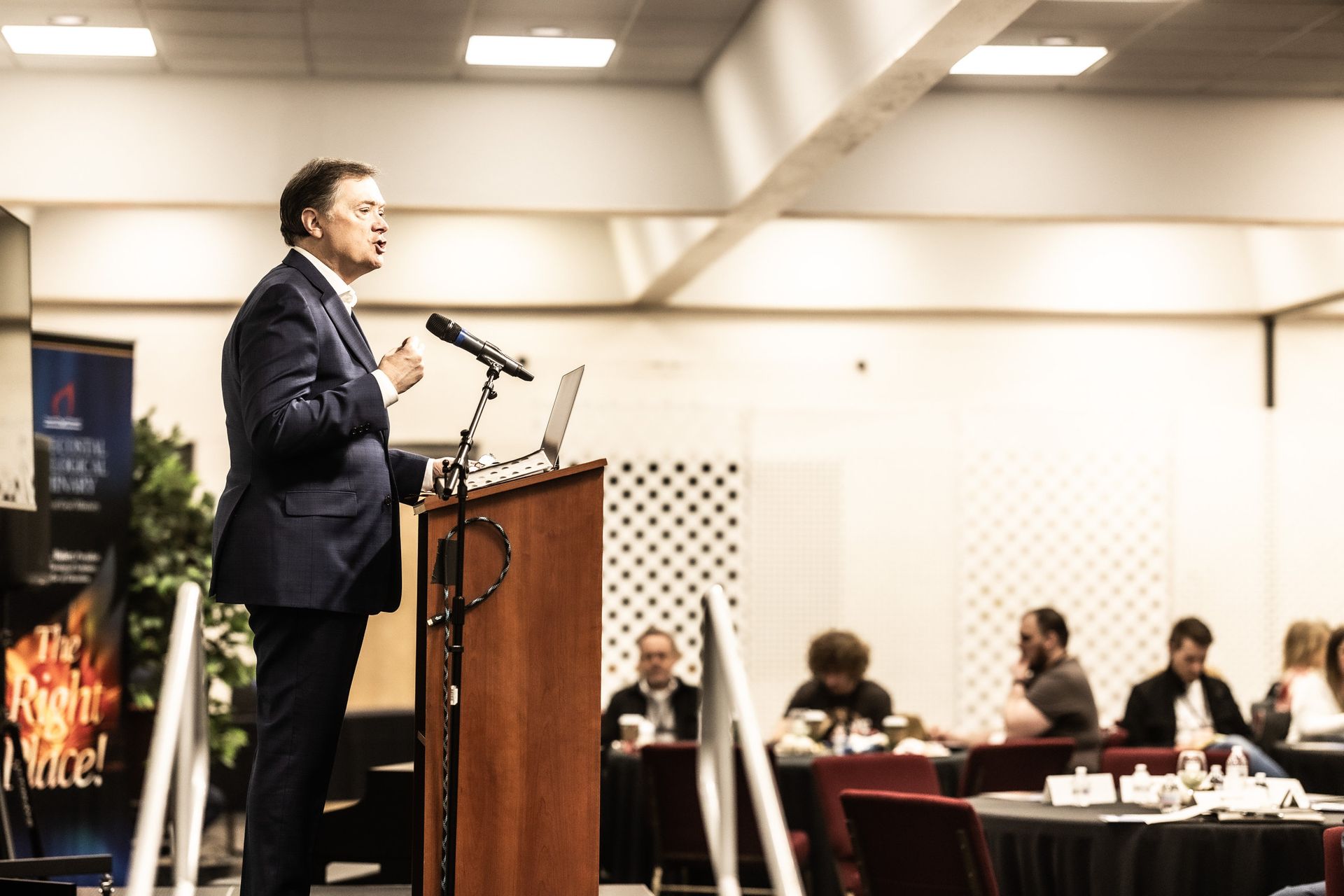 A man in a suit is standing at a podium giving a speech.
