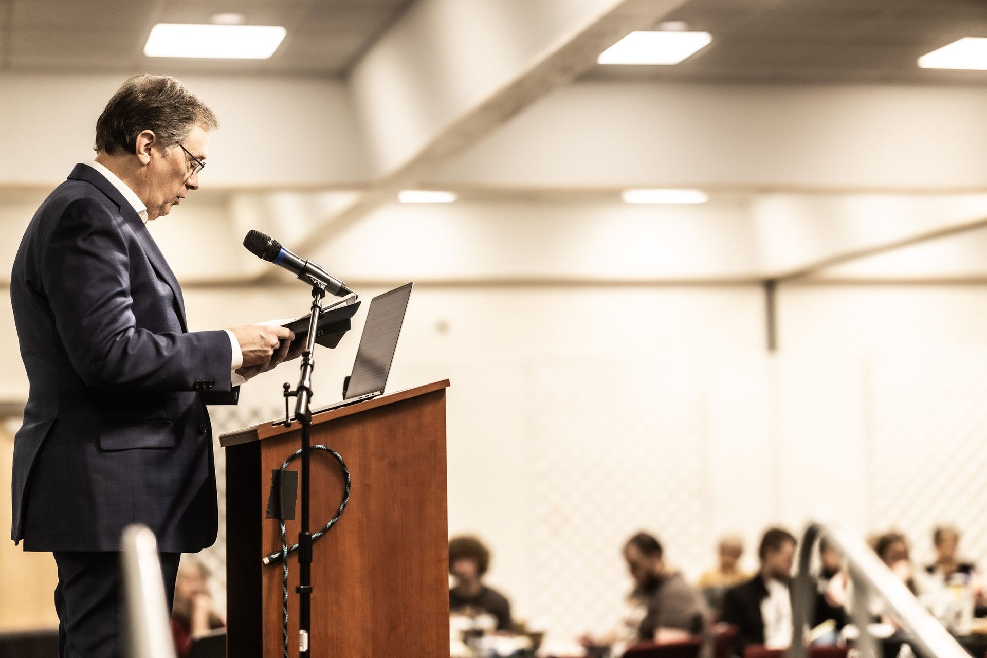 A man in a suit is standing at a podium giving a speech.