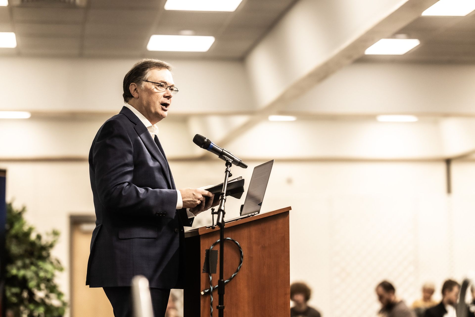 A man in a suit is standing at a podium giving a speech.