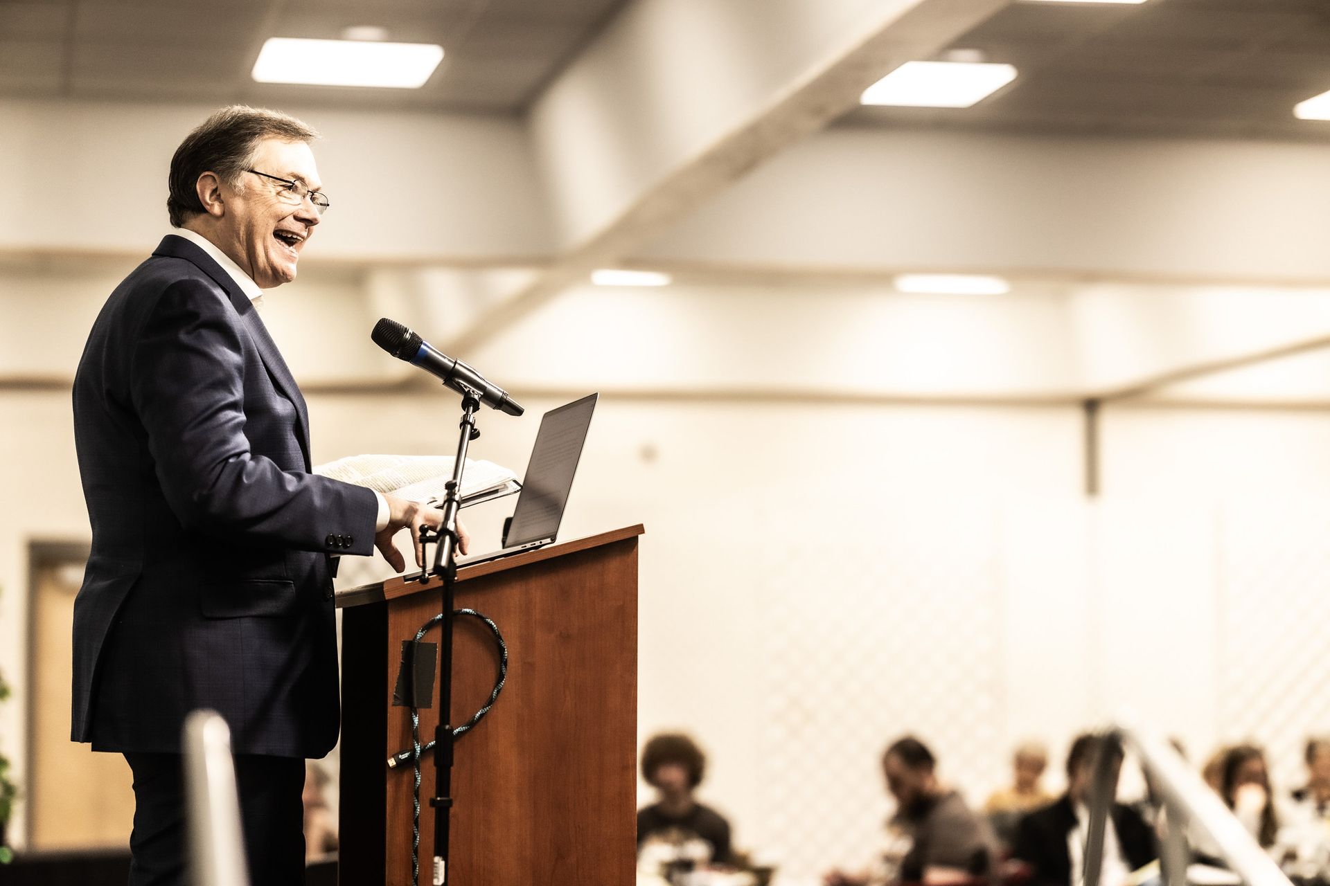 A man in a suit is standing at a podium giving a speech.