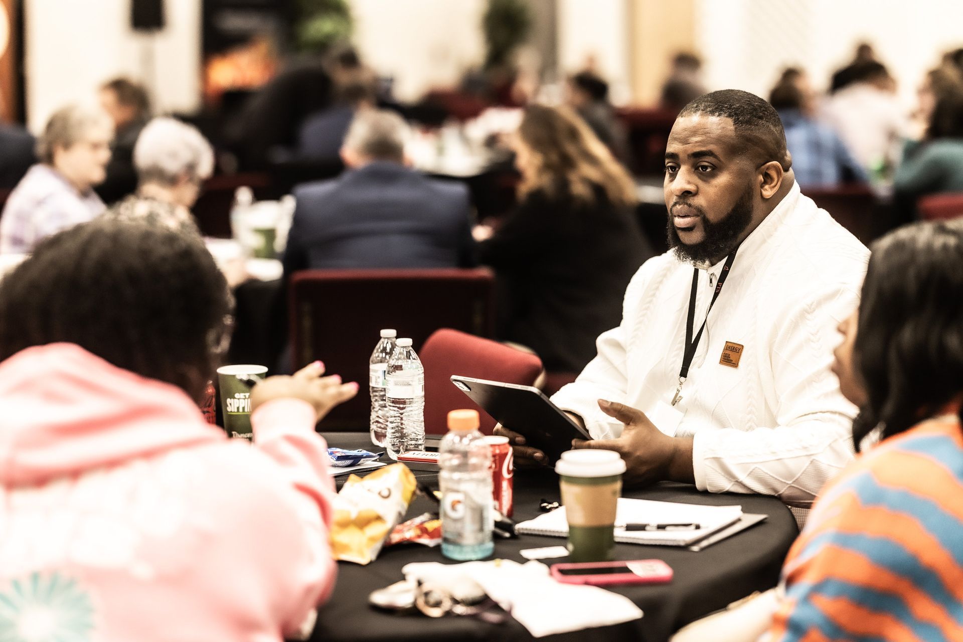 A man is sitting at a table talking to a group of people.