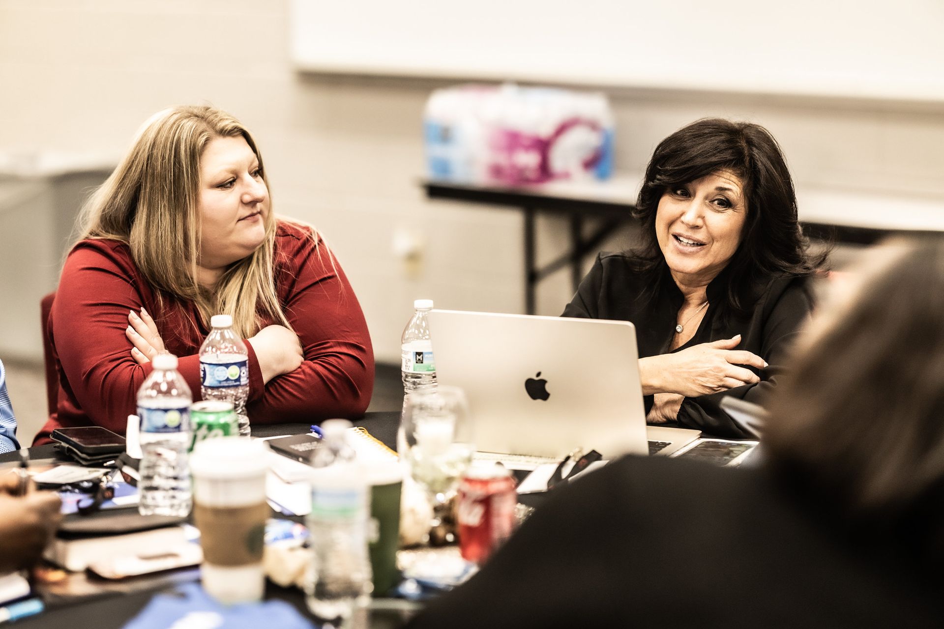 Two women are sitting at a table with a laptop.