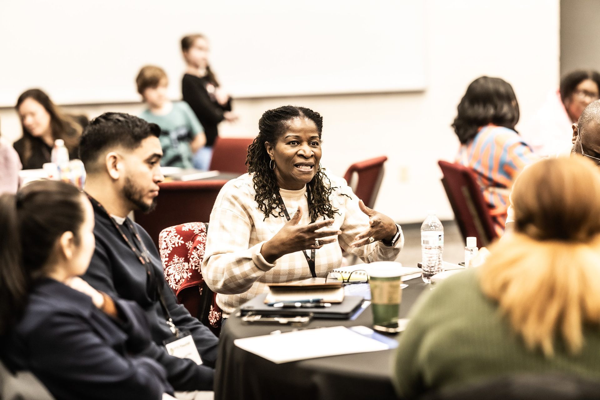A woman is sitting at a table talking to a group of people.