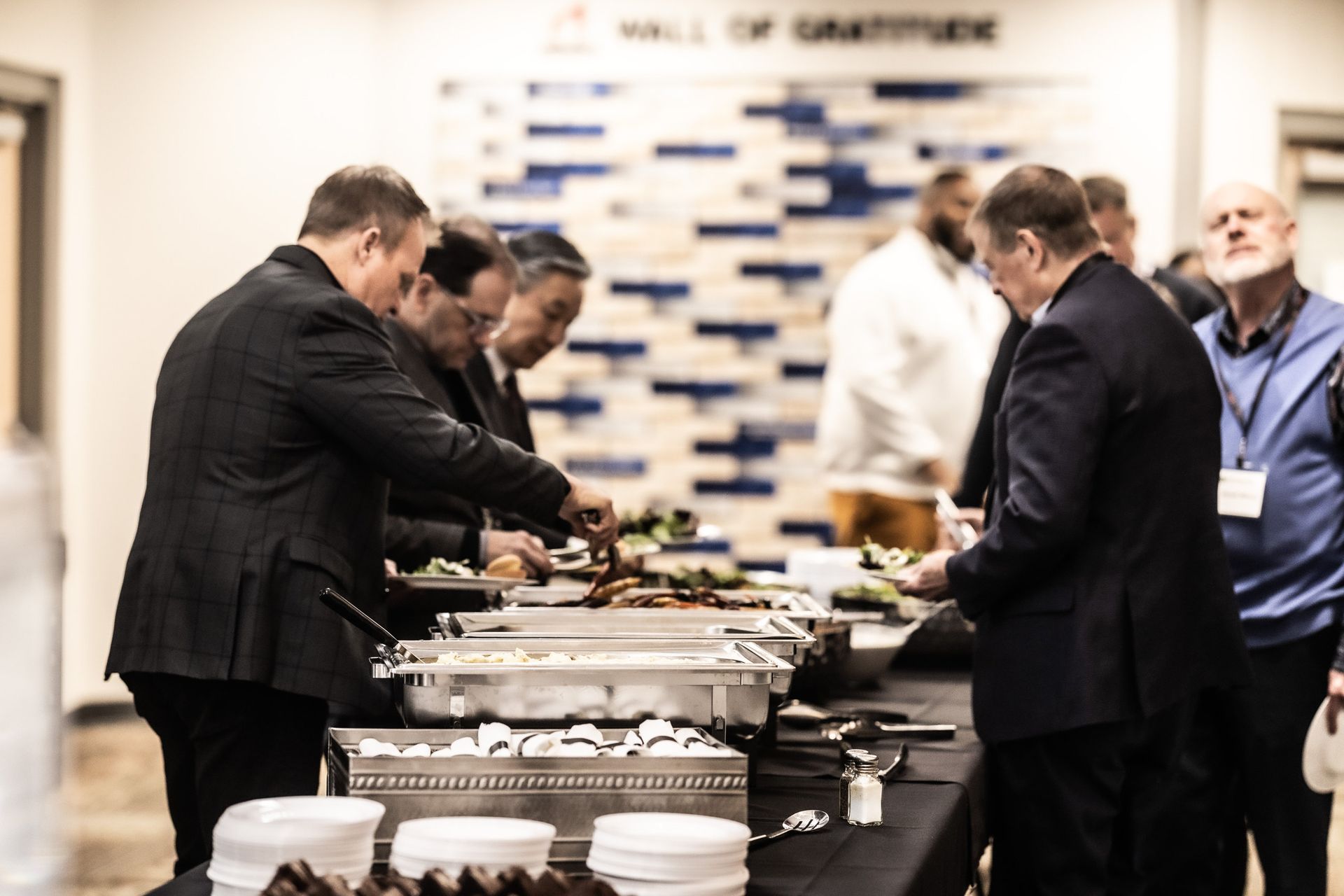 A group of men are standing around a table eating food.