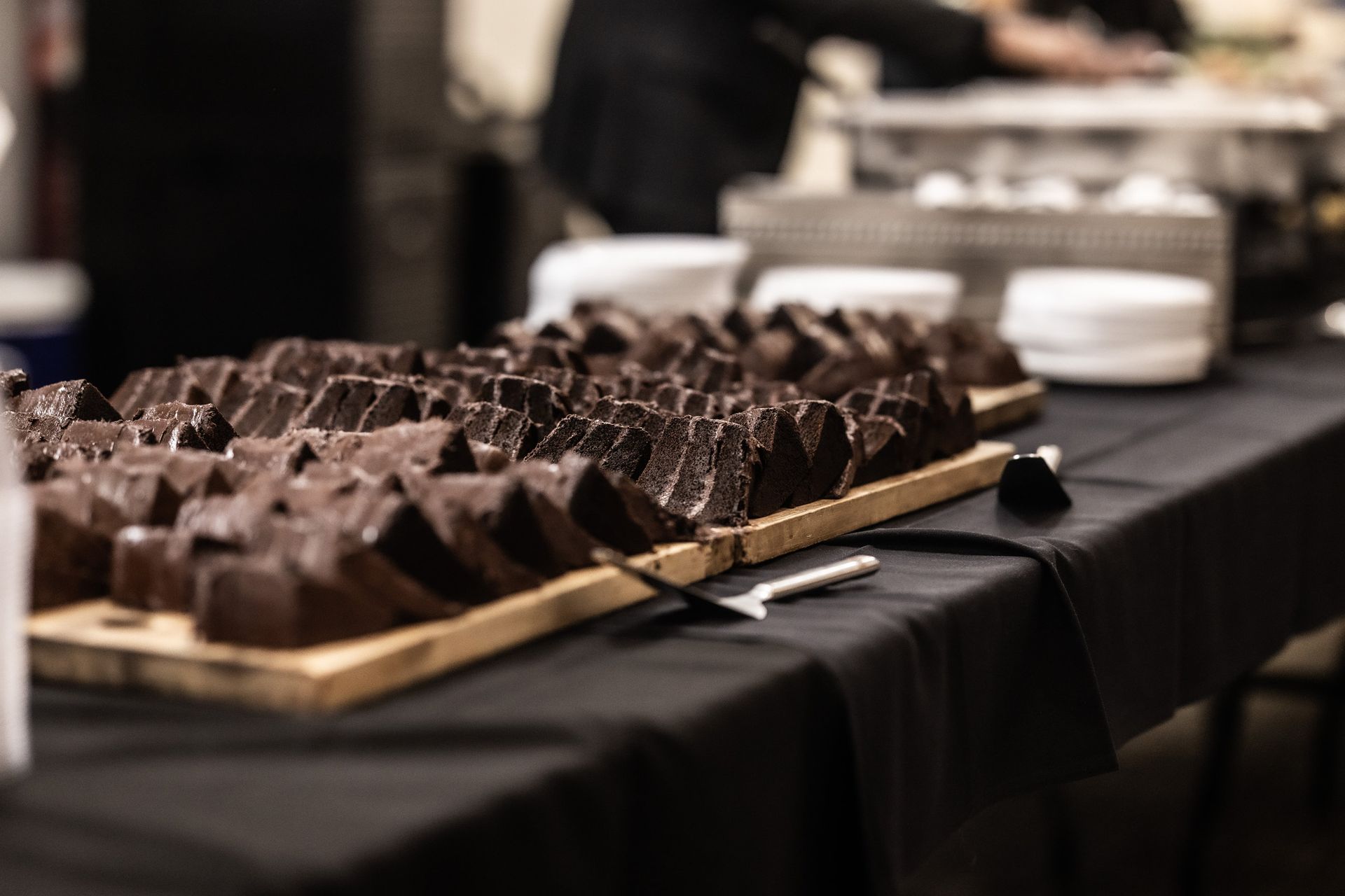 A wooden tray filled with chocolate brownies on a table.