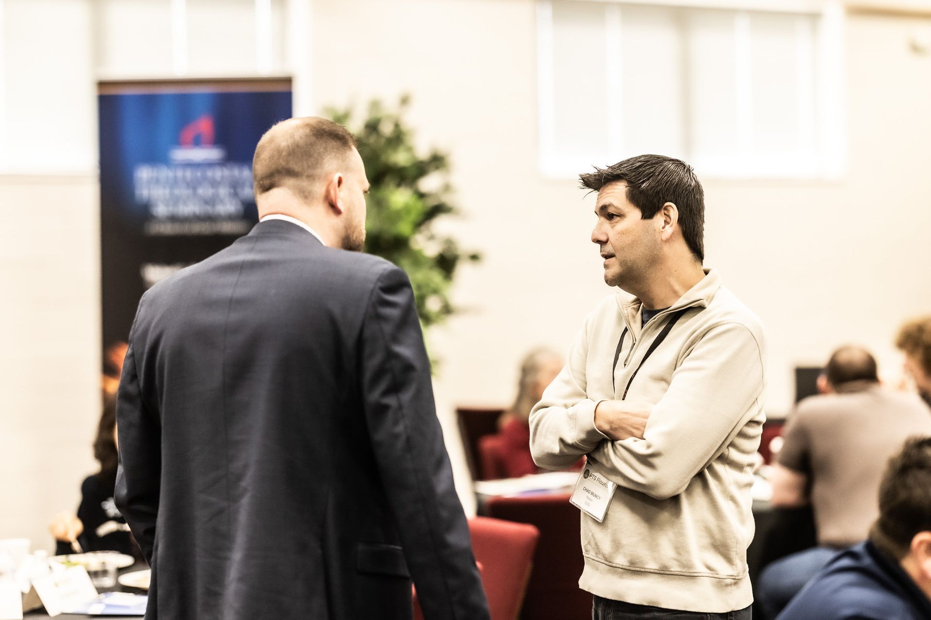Two men are standing next to each other in a room talking to each other.