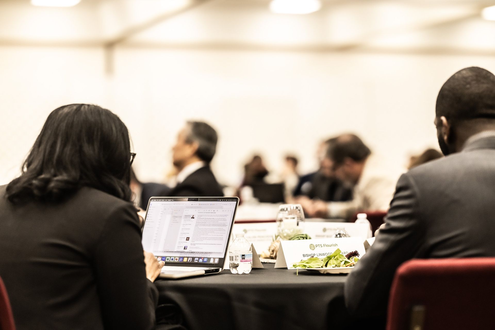 A man and a woman are sitting at a table with laptops.