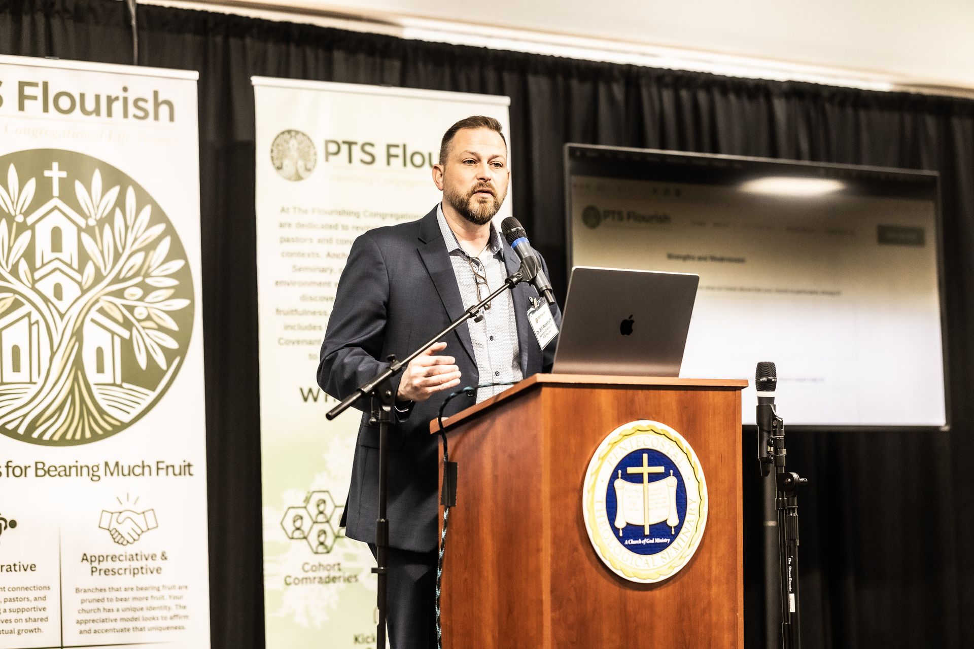 A man in a suit is standing at a podium giving a presentation.