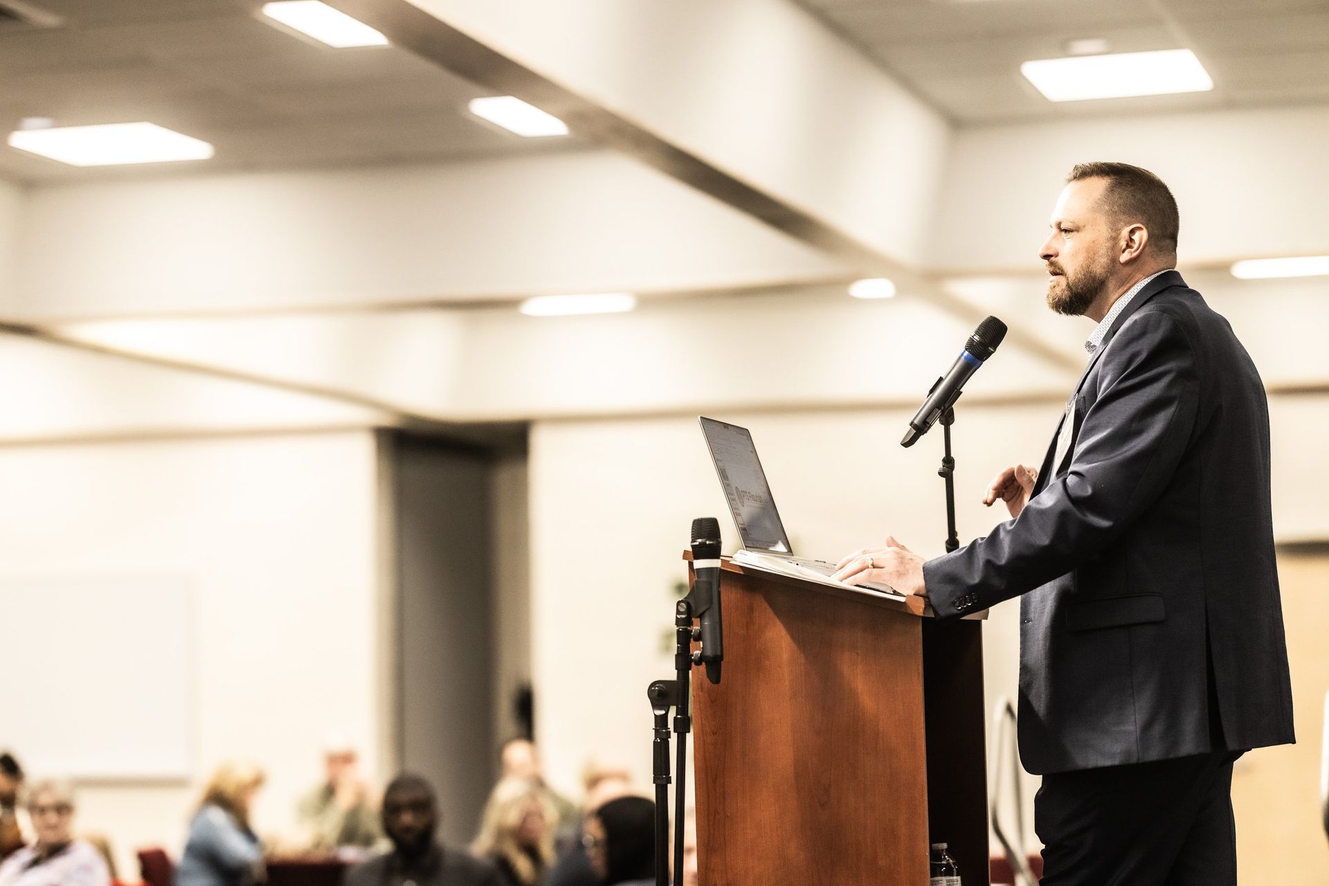 A man is standing at a podium giving a presentation to a group of people.