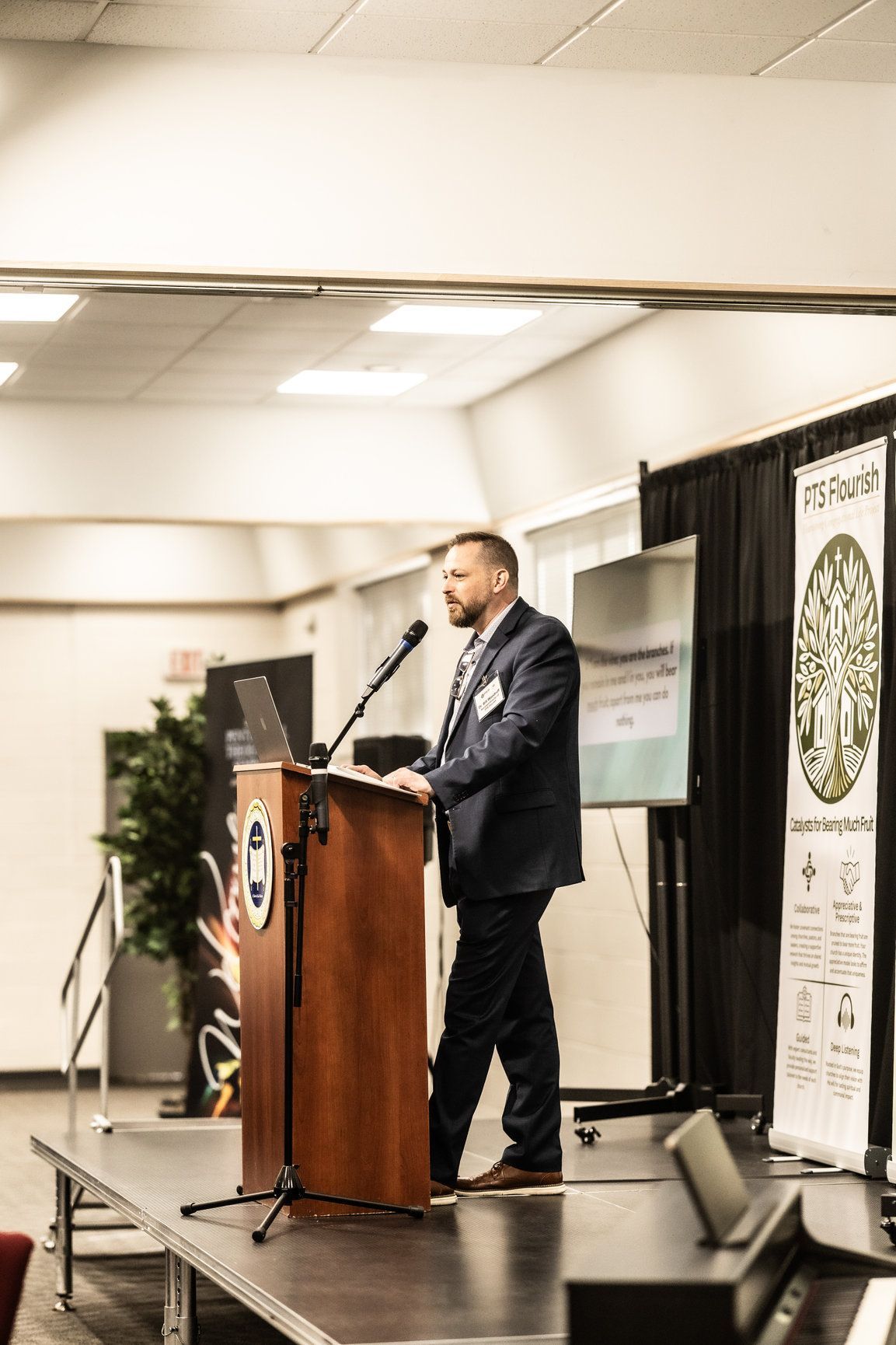 A man in a suit is standing at a podium giving a presentation.