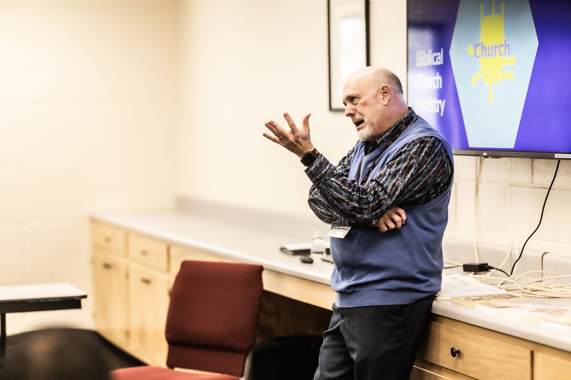 A man is standing in front of a television in a room.