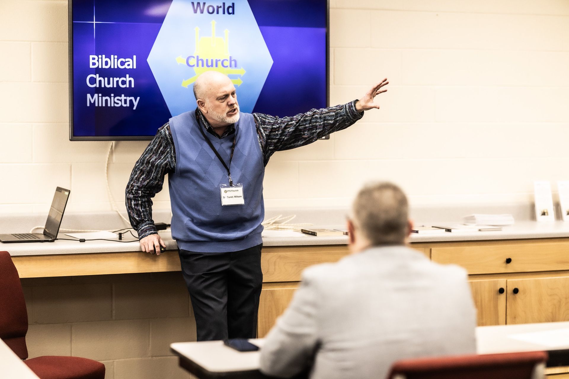 A man is giving a presentation to a group of people in a classroom.