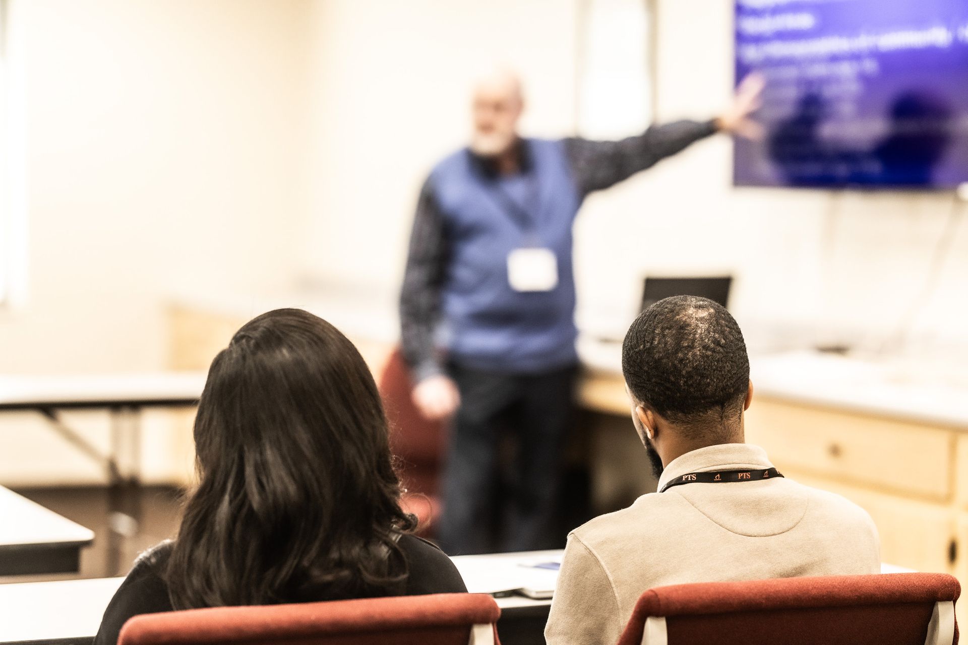 A man is giving a presentation to a group of people in a classroom.