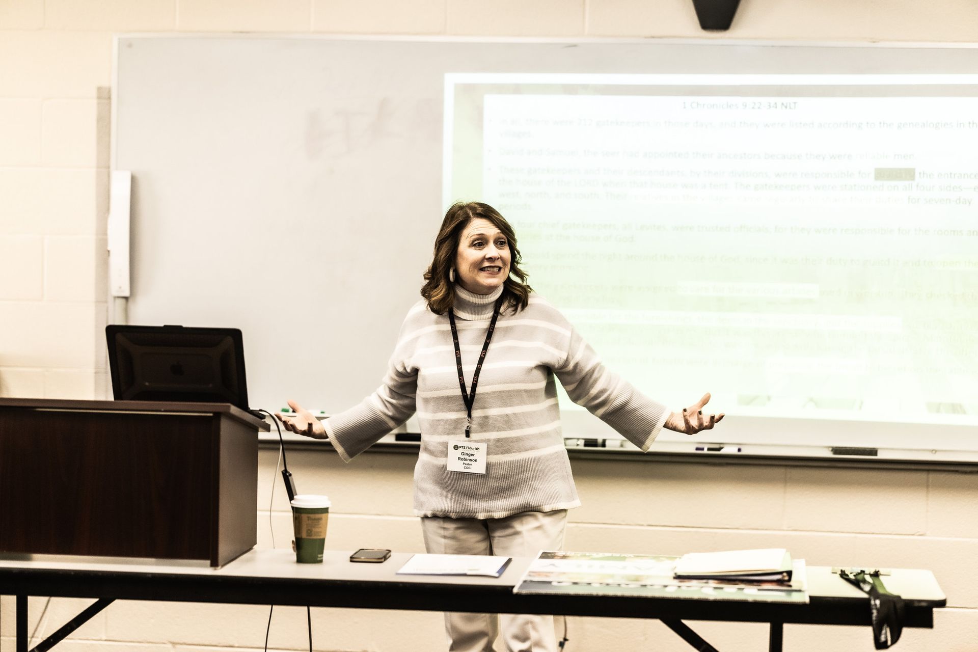 A woman is standing in front of a whiteboard in a classroom.