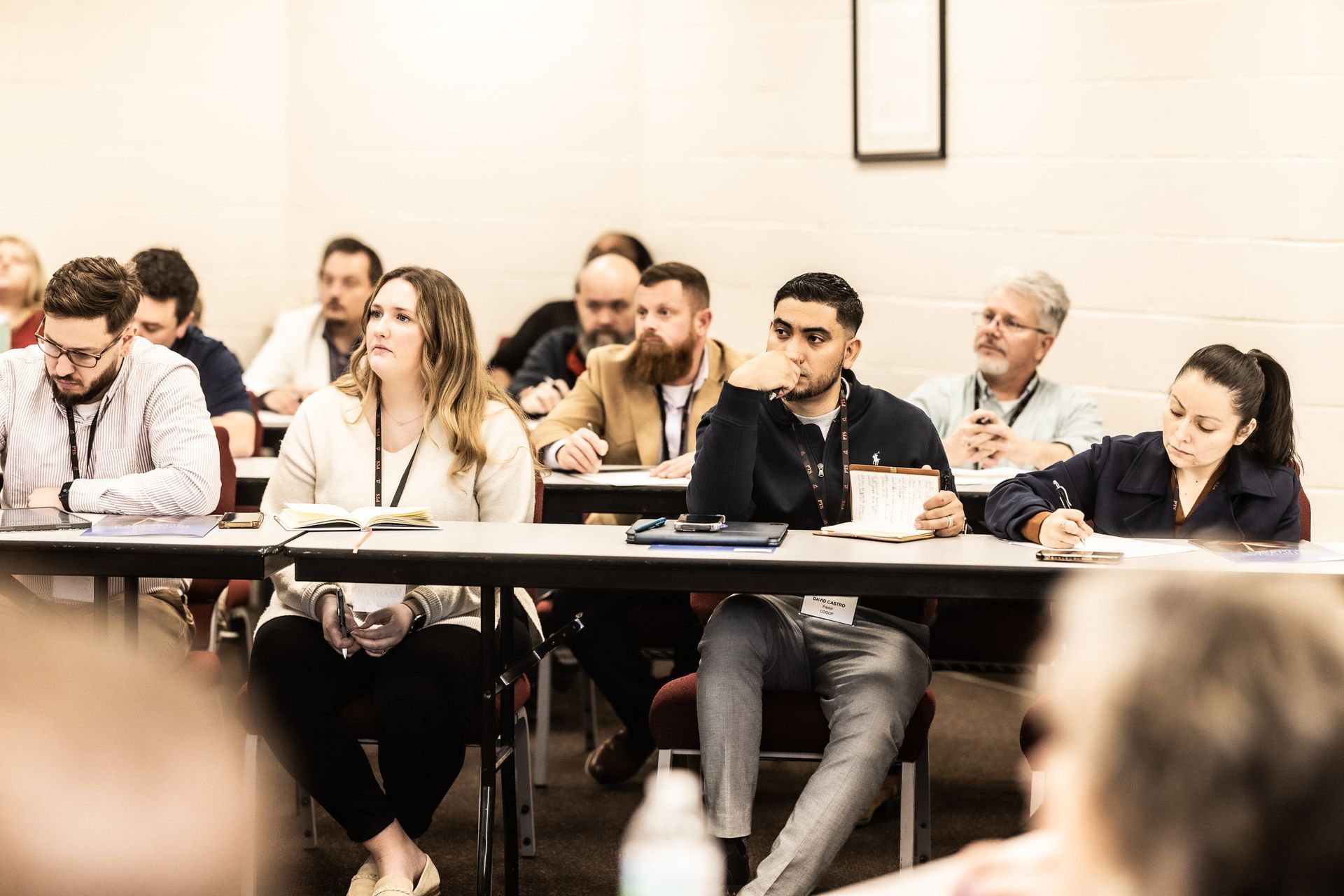 A group of people are sitting at tables in a classroom.