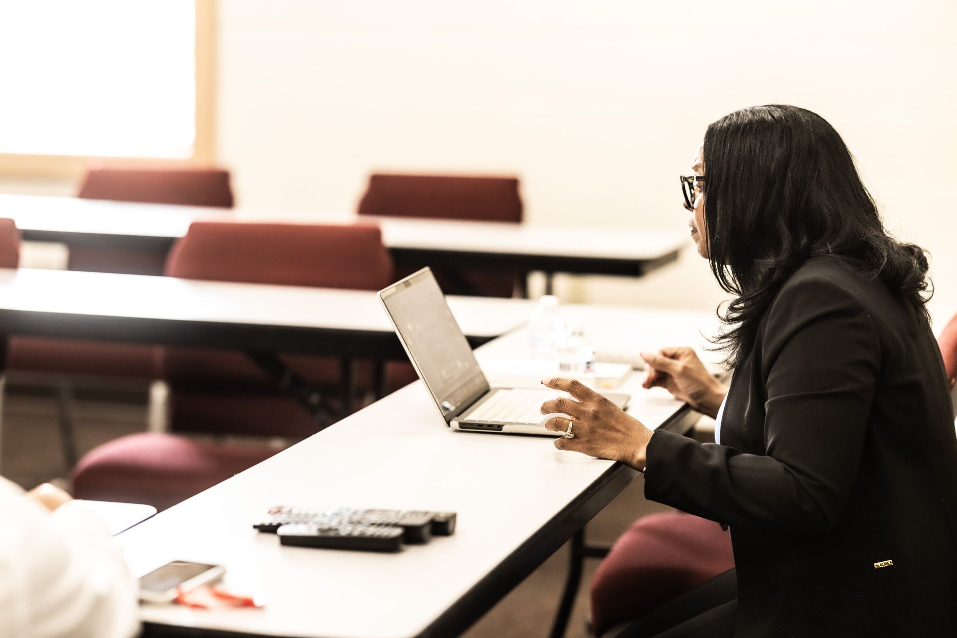 A woman is sitting at a table with a laptop on it.
