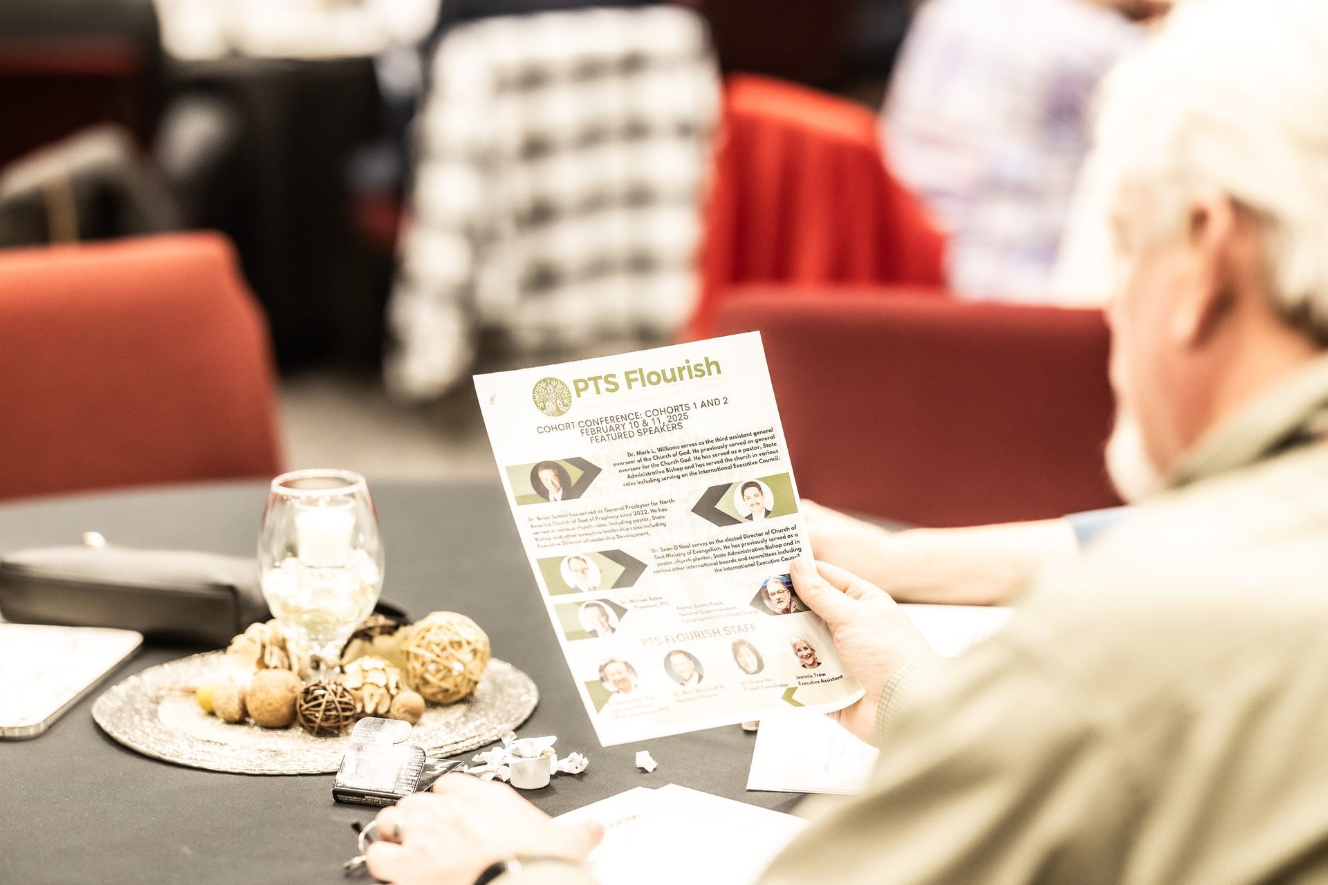 A man is sitting at a table holding a piece of paper.