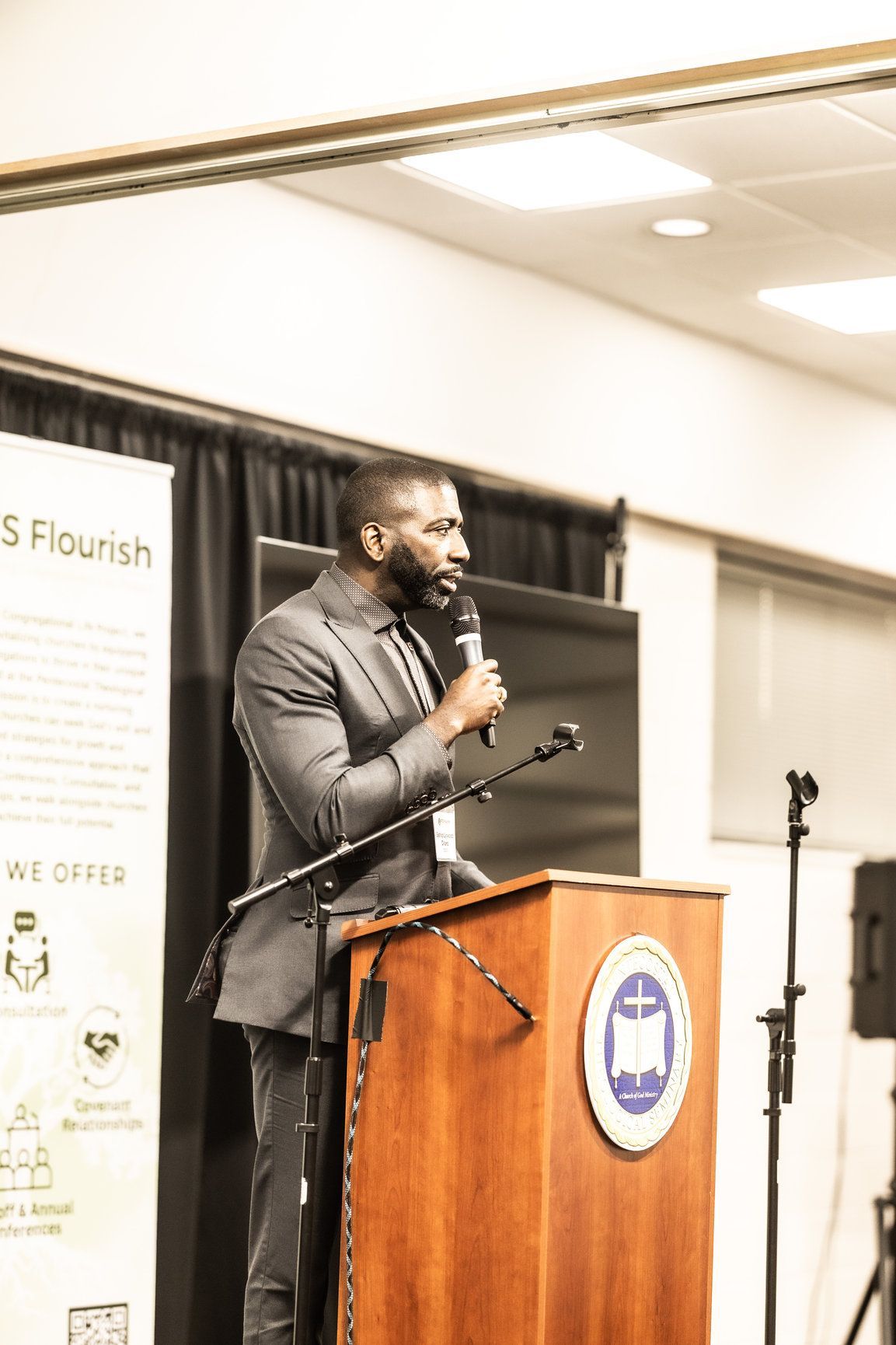 A man in a suit is standing at a podium holding a microphone.