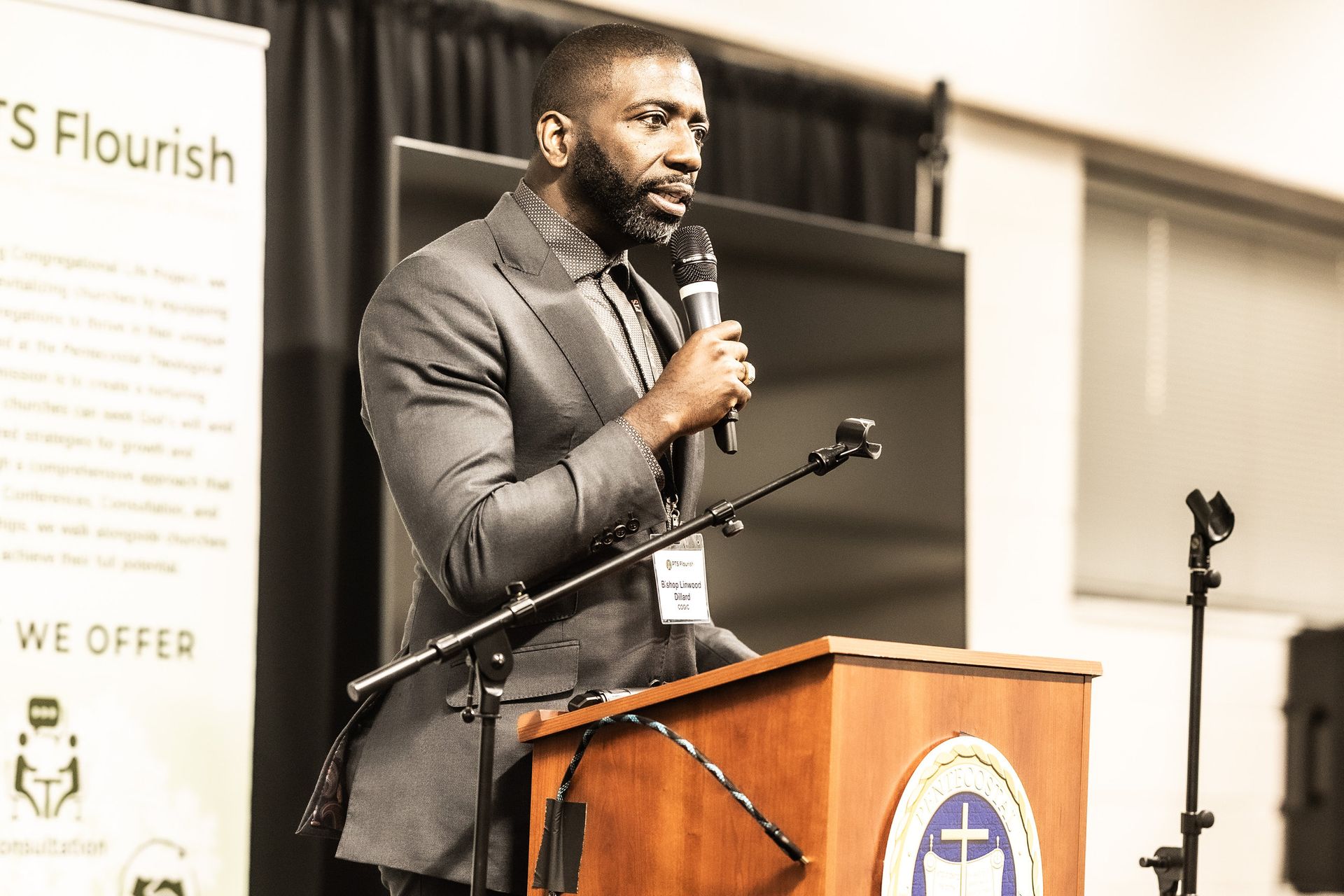 A man in a suit is standing at a podium holding a microphone.