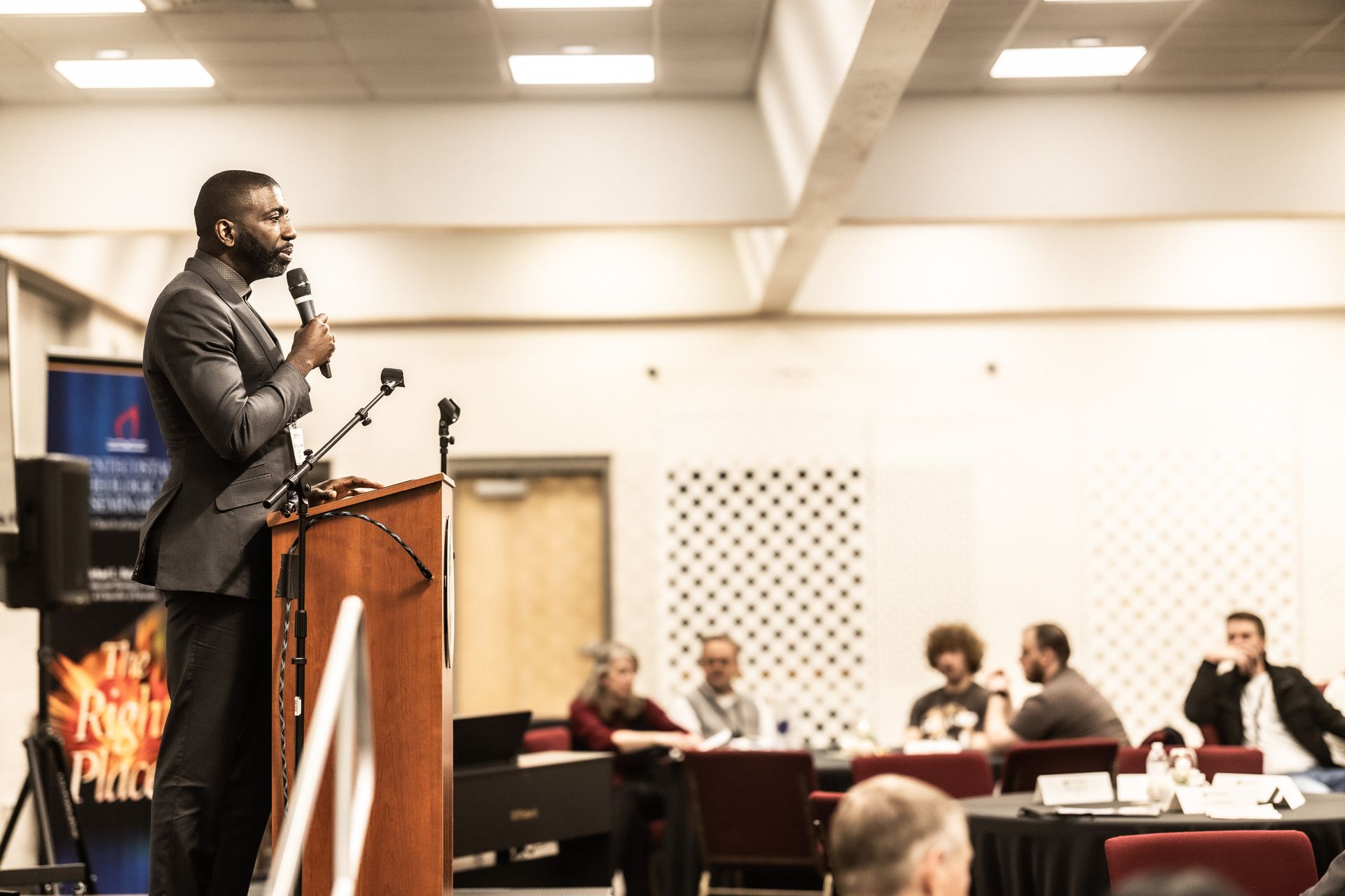A man is standing at a podium giving a speech to a group of people.