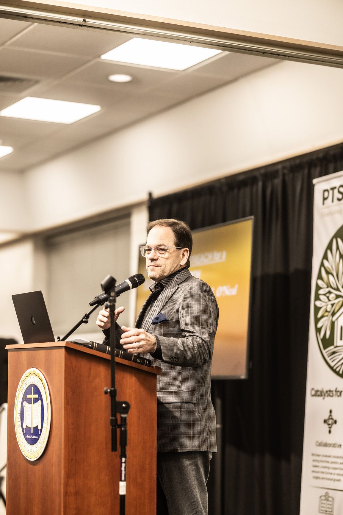 A man is standing at a podium speaking into a microphone.