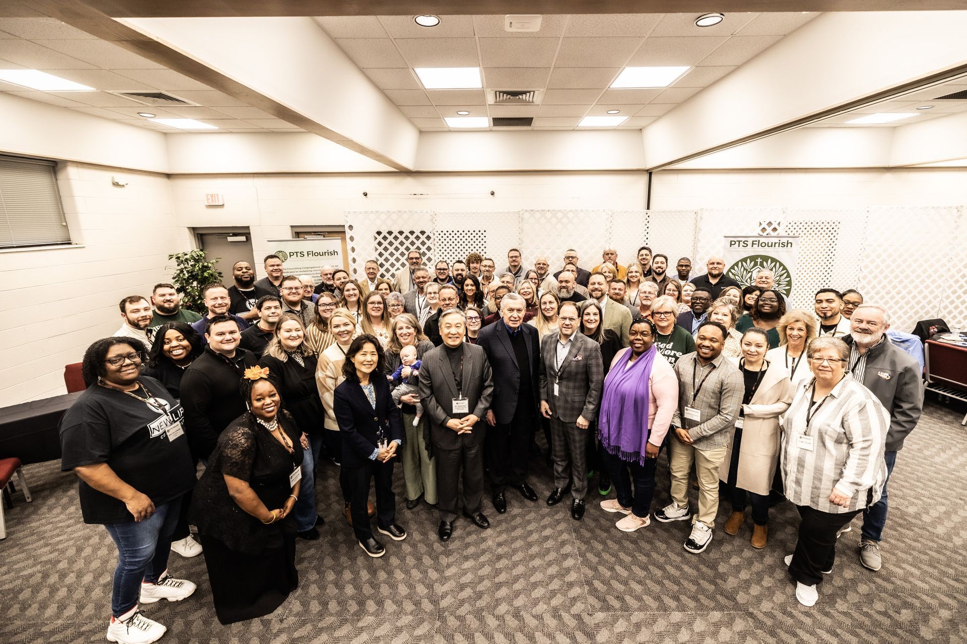 A large group of people are posing for a picture in a room.