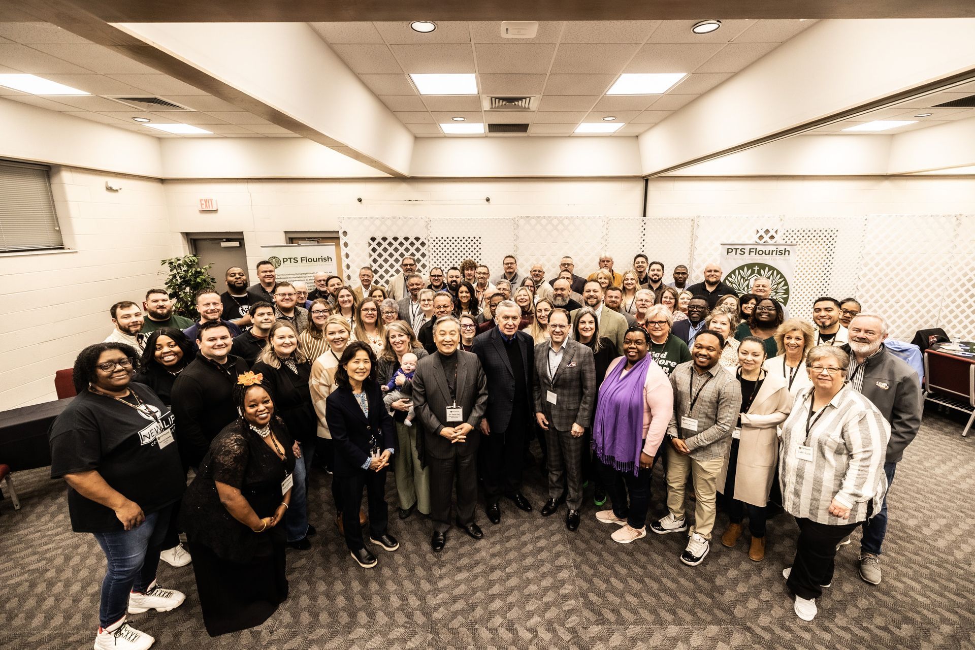 A large group of people are posing for a picture in a room.