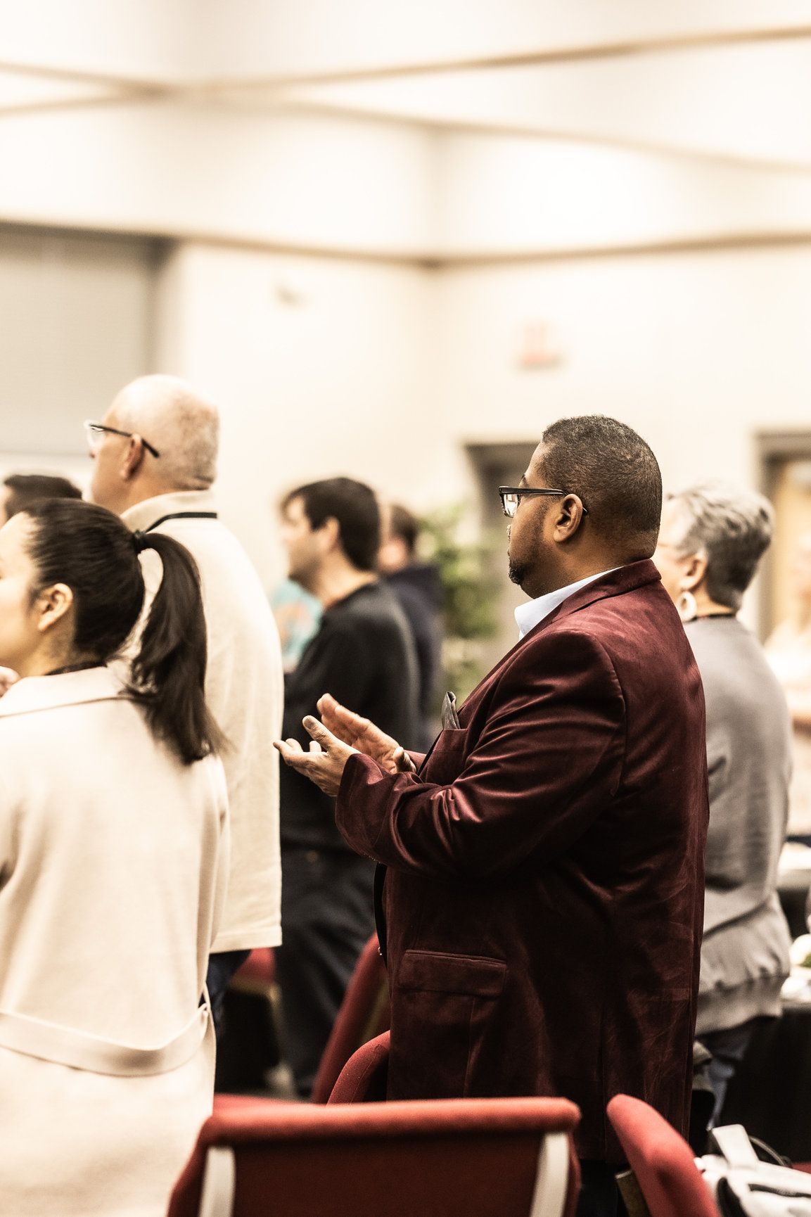 A group of people are standing in a room talking to each other.