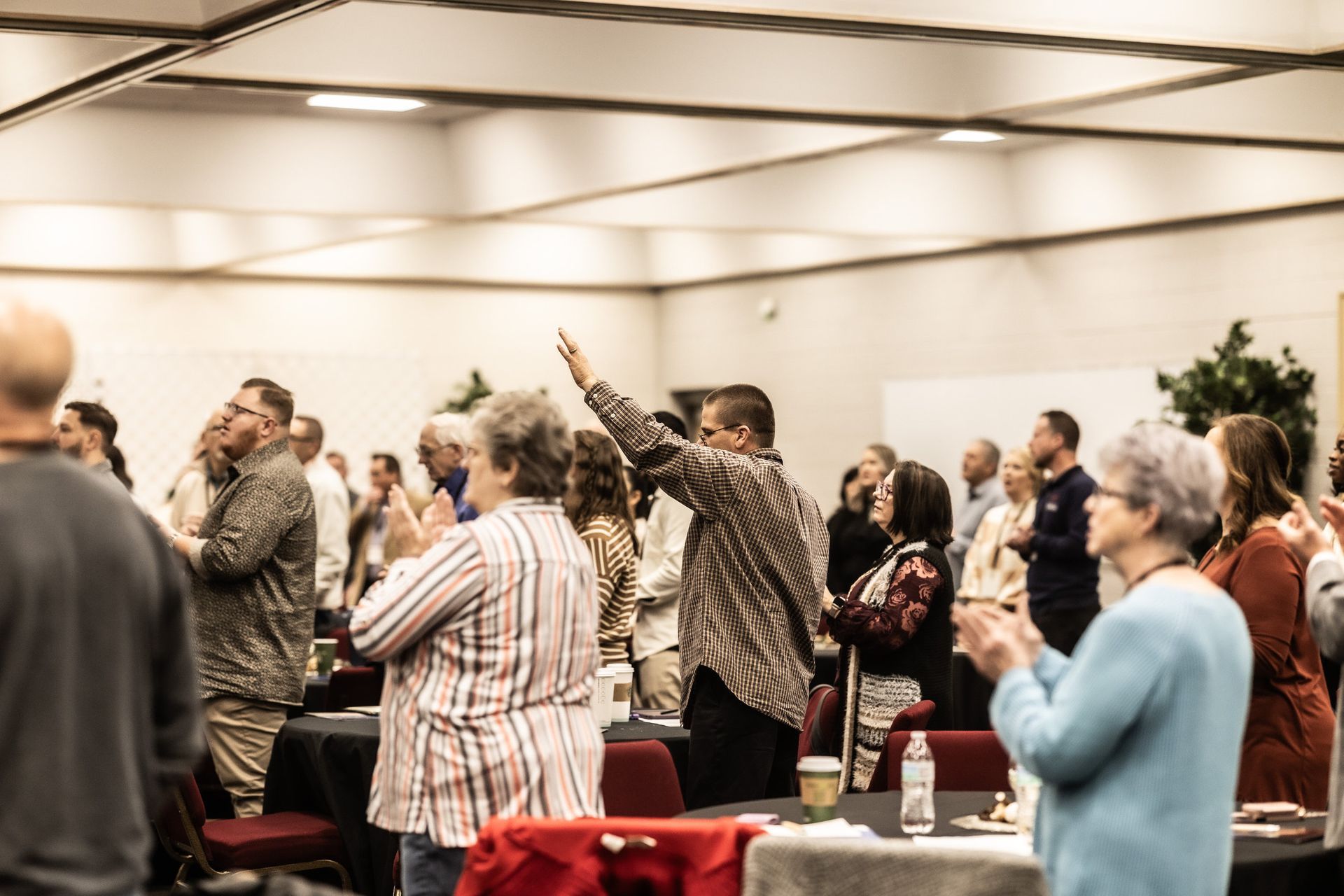 A group of people are standing in a room applauding.