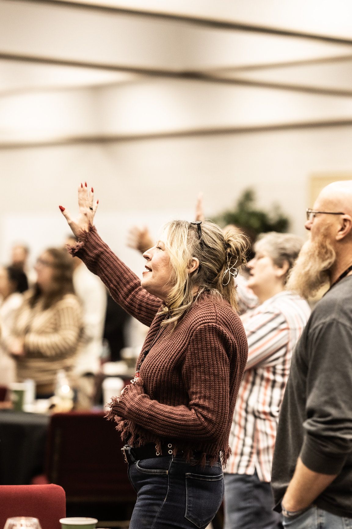 A group of people are standing in a room with their hands in the air.