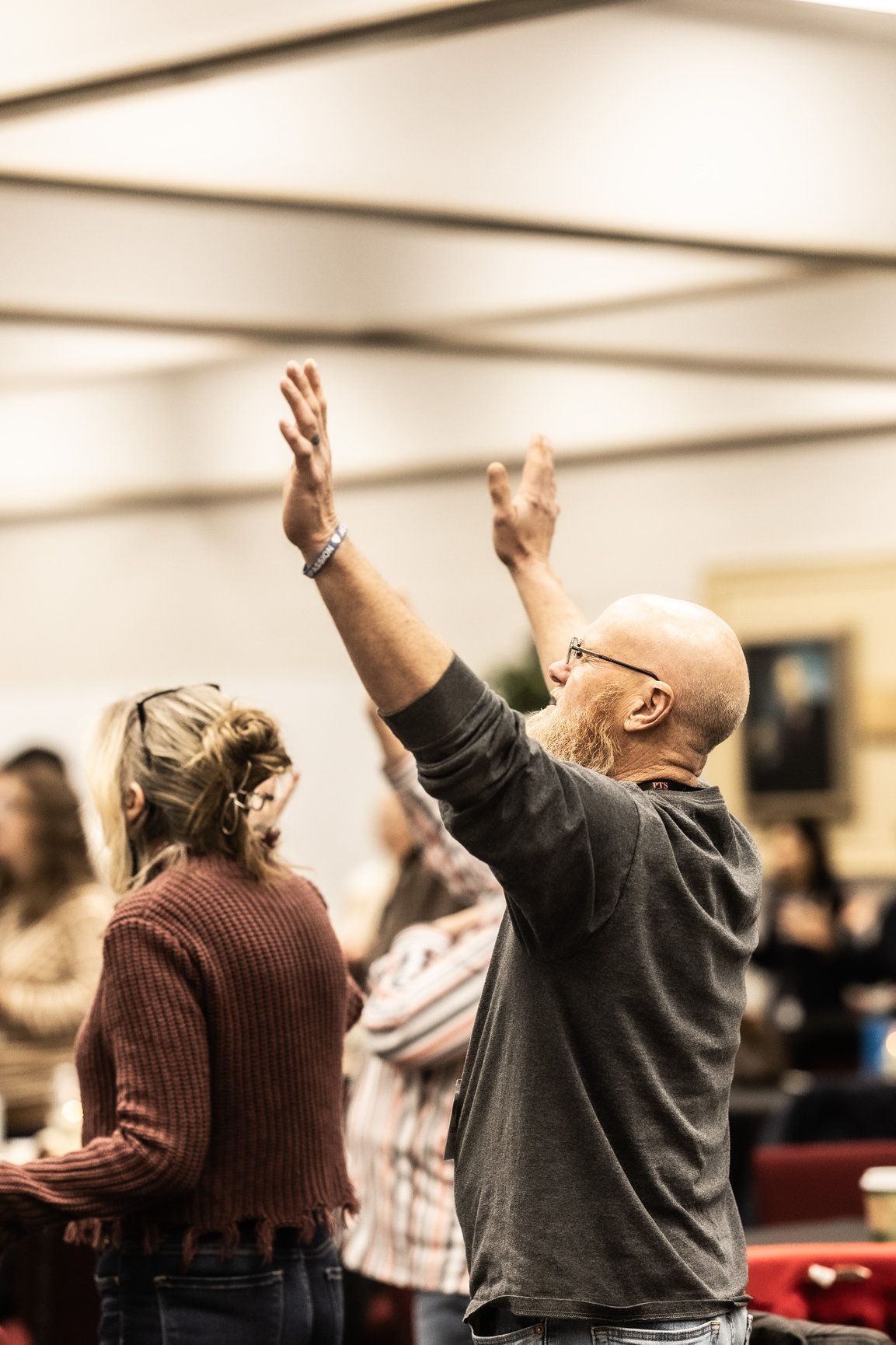 A man is raising his hands in the air in a crowded room.