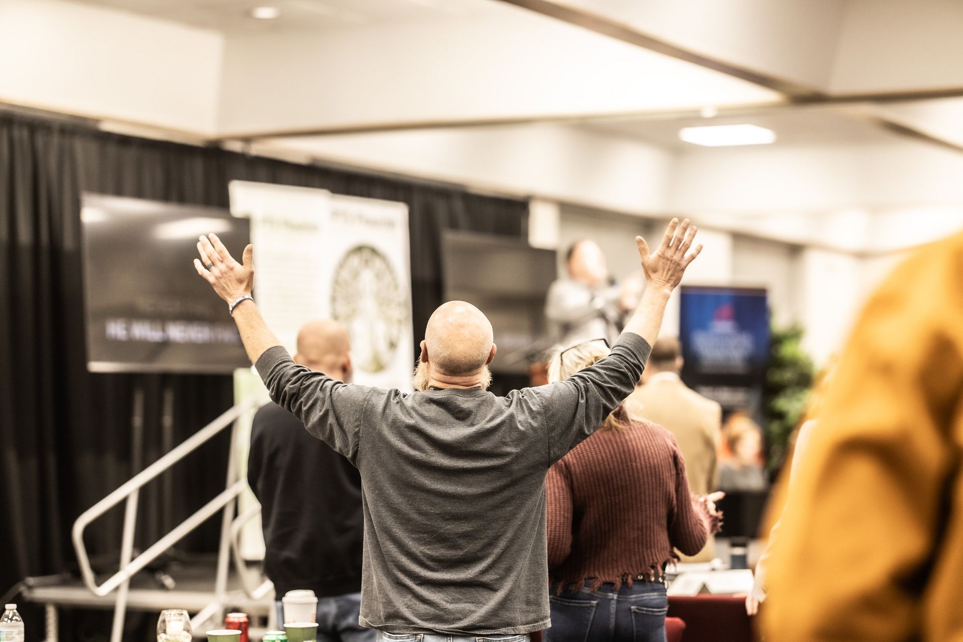 A group of people are standing in a room with their hands in the air.