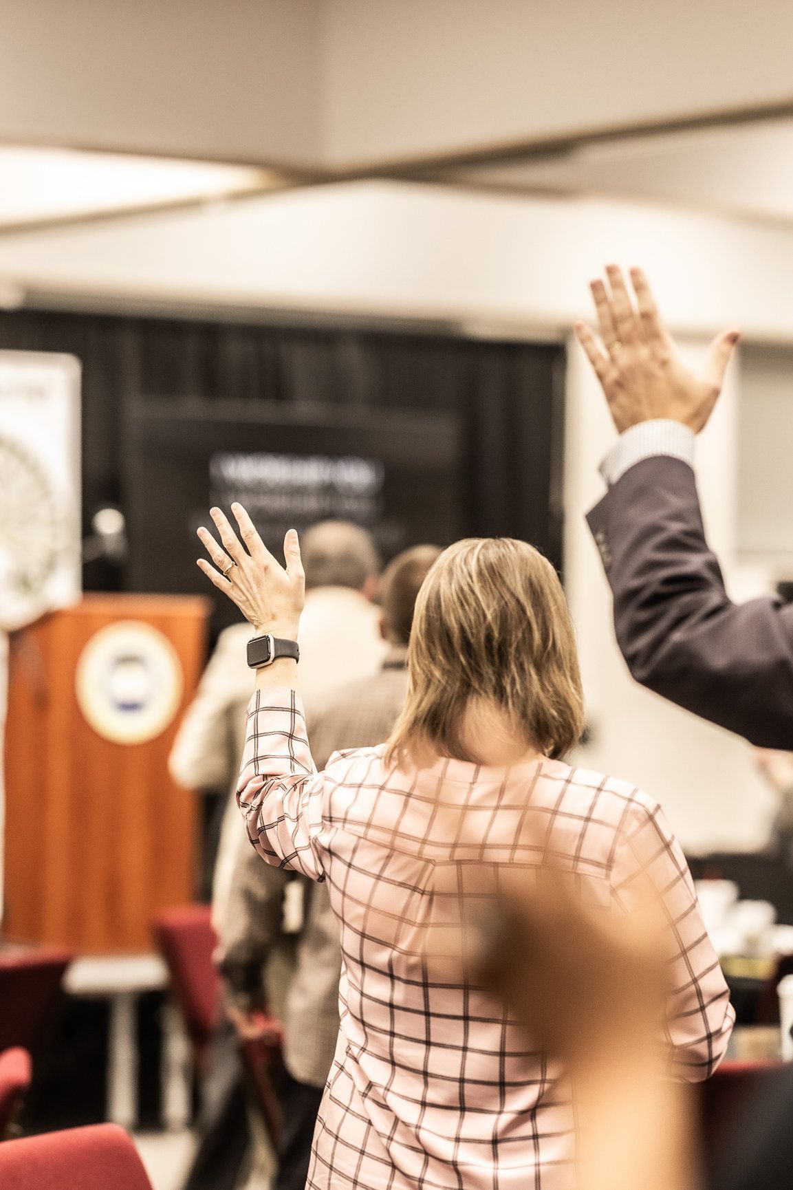 A group of people are raising their hands in the air in a room.