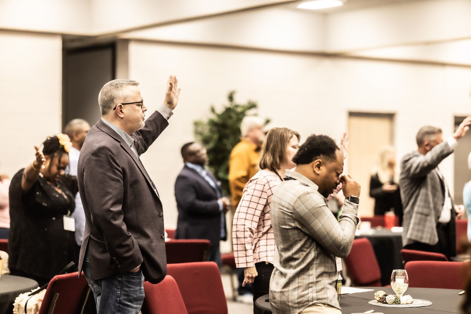 A group of people are standing in a room with their hands in the air.