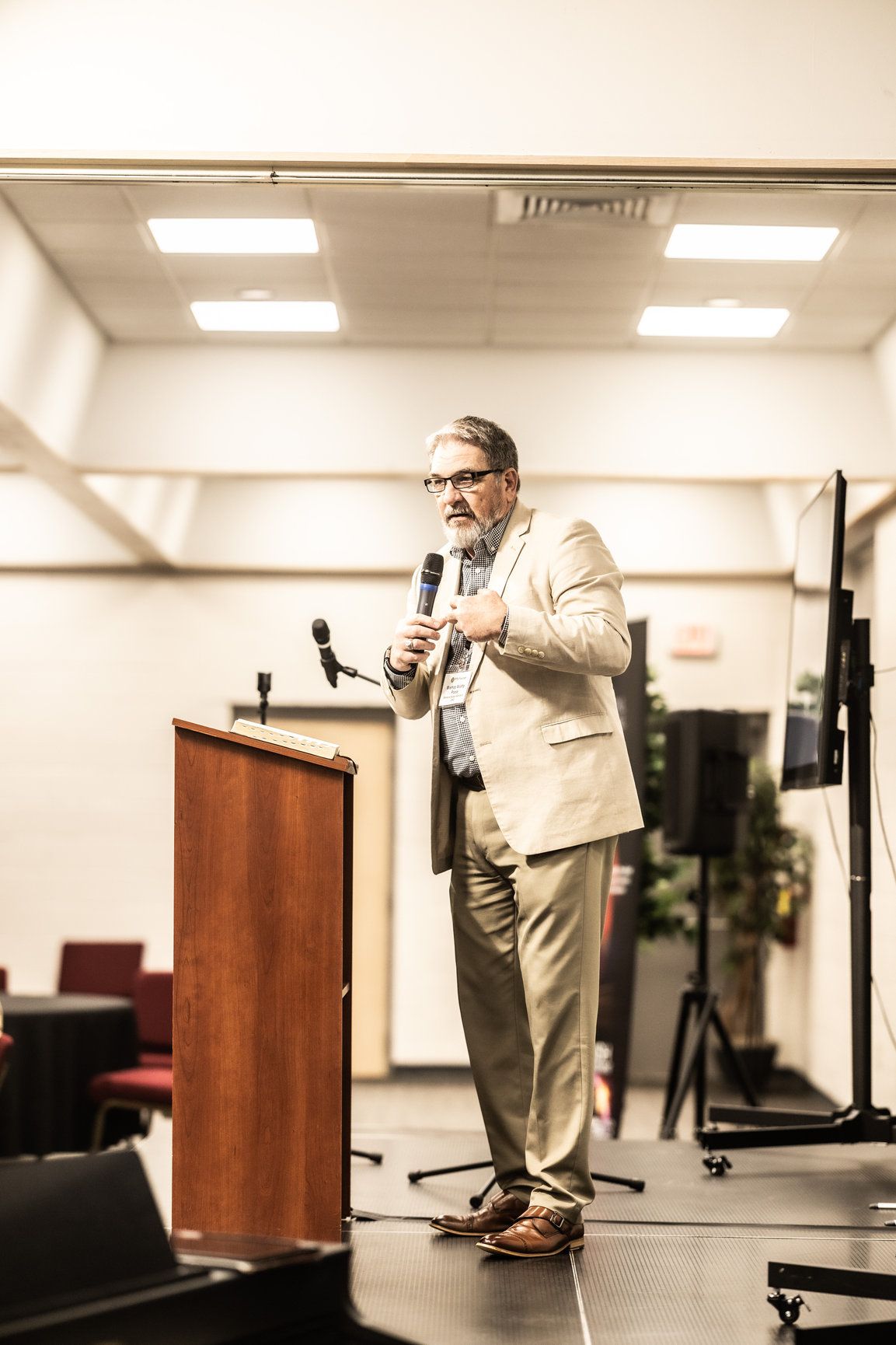 A man in a suit is standing at a podium holding a microphone.