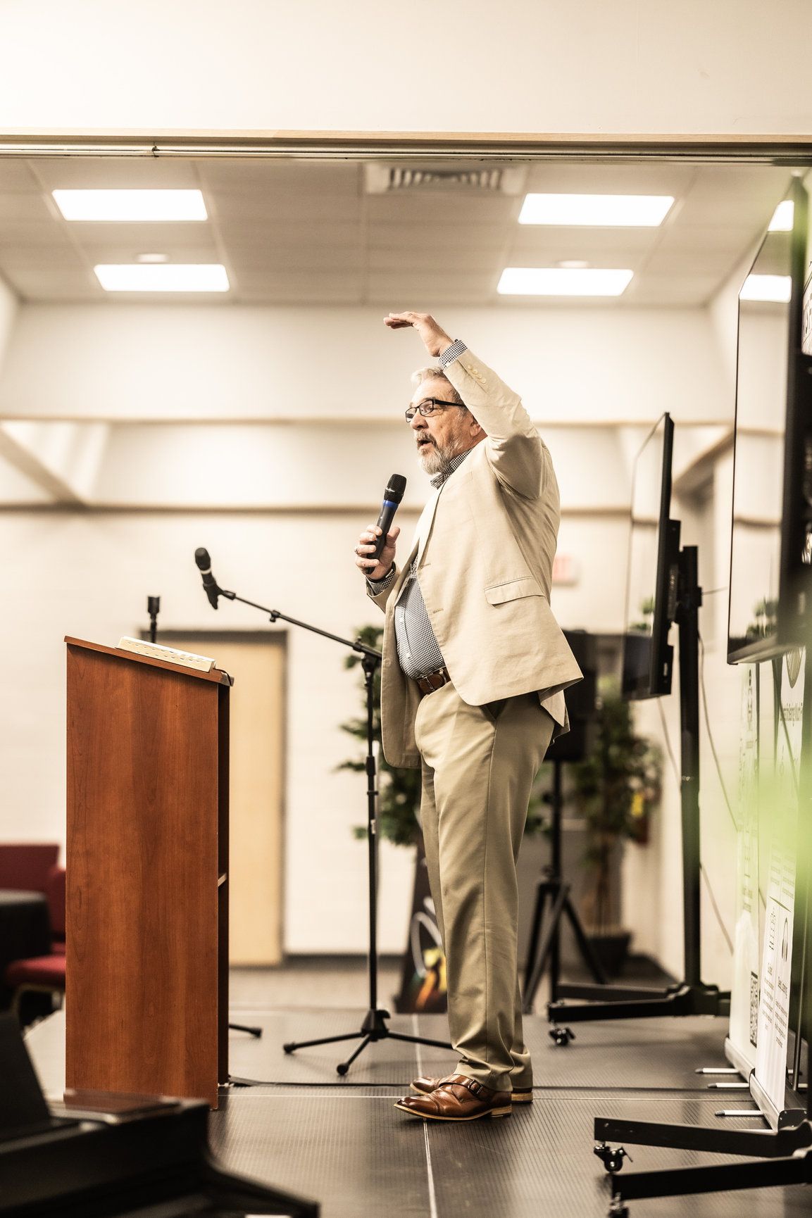 A man is standing in front of a podium holding a microphone.