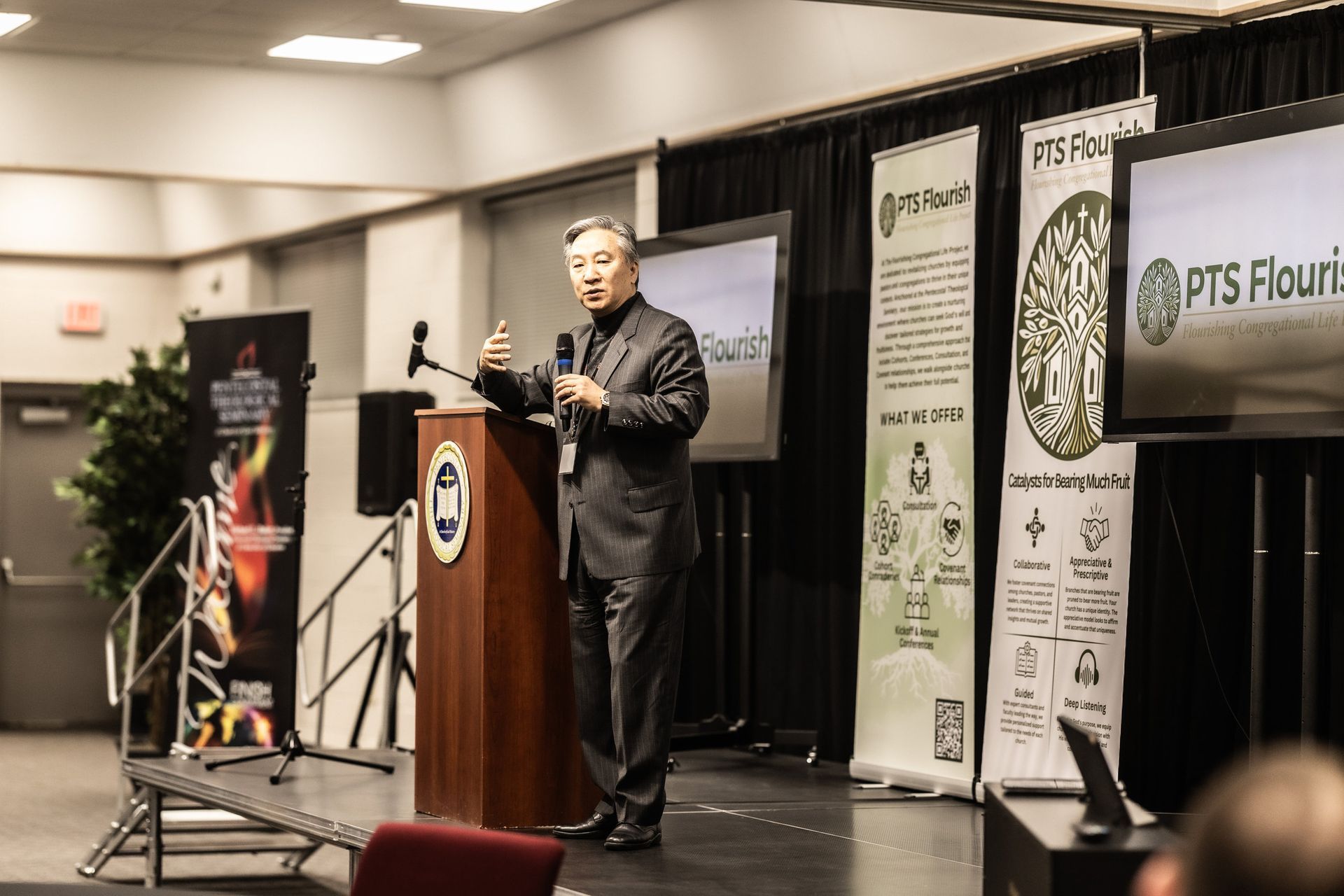 A man in a suit is standing at a podium giving a presentation.