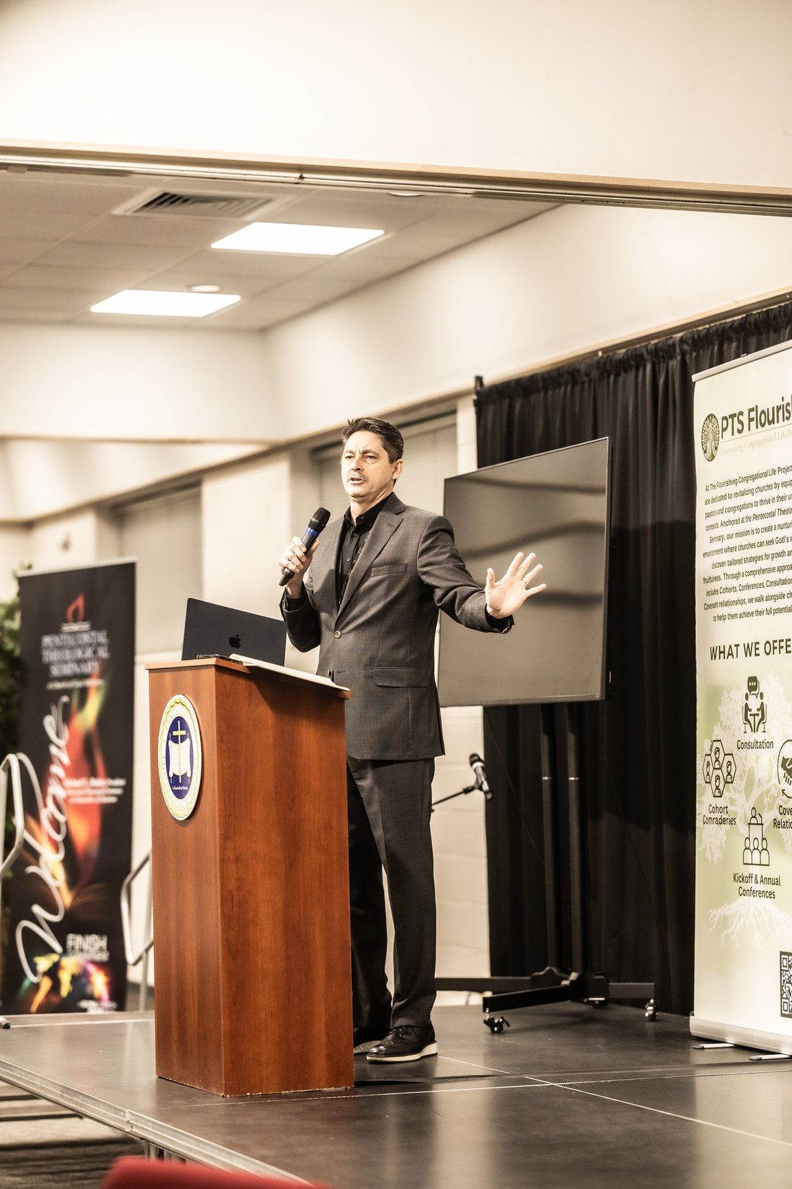 A man in a suit is standing at a podium giving a presentation.
