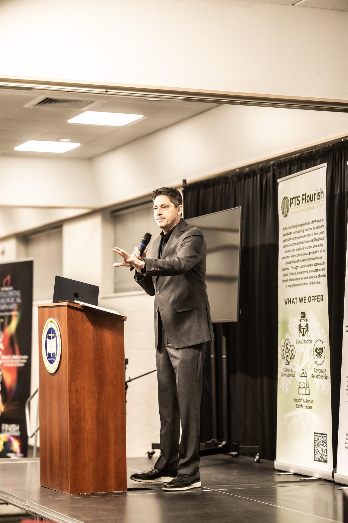 A man in a suit is standing at a podium giving a presentation.