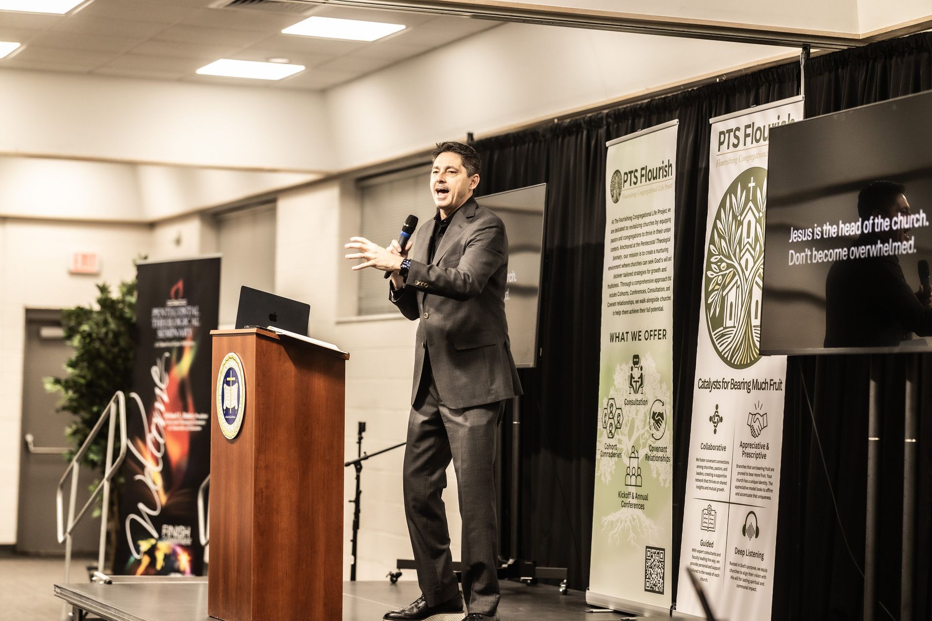A man in a suit is standing at a podium giving a presentation.