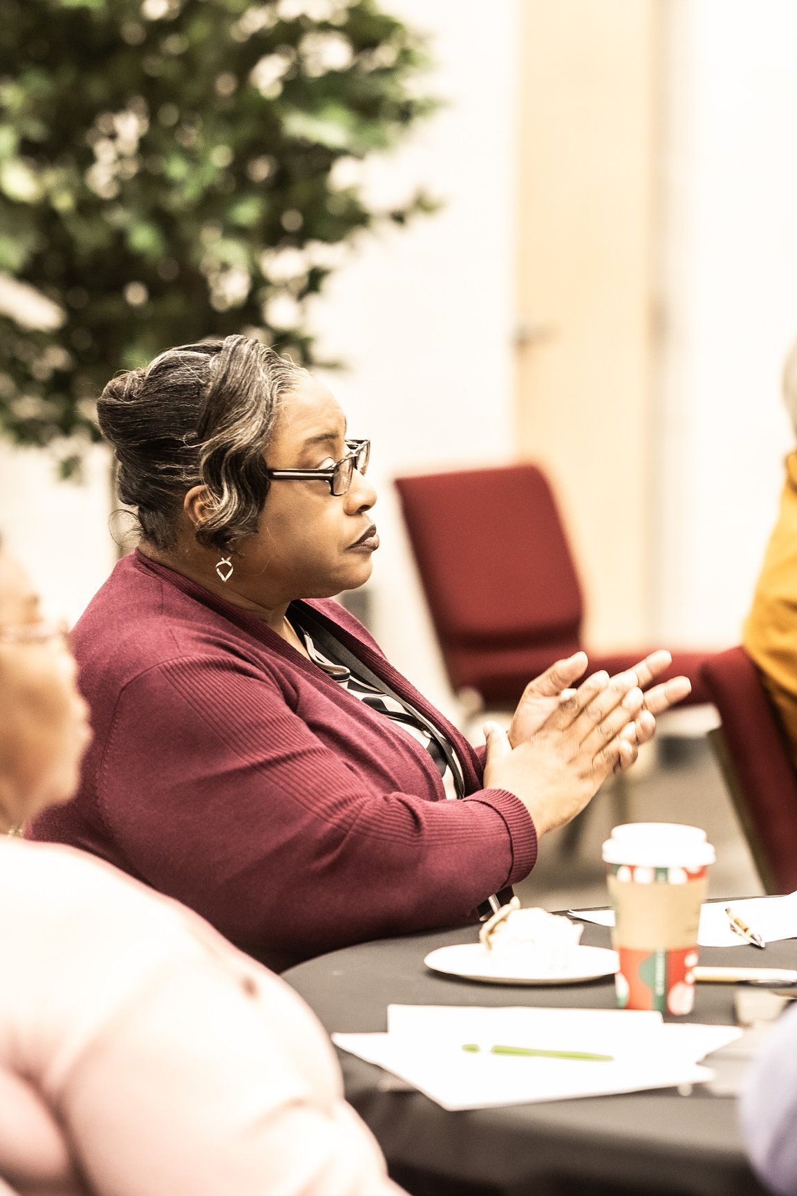 A woman is clapping her hands while sitting at a table with other people.